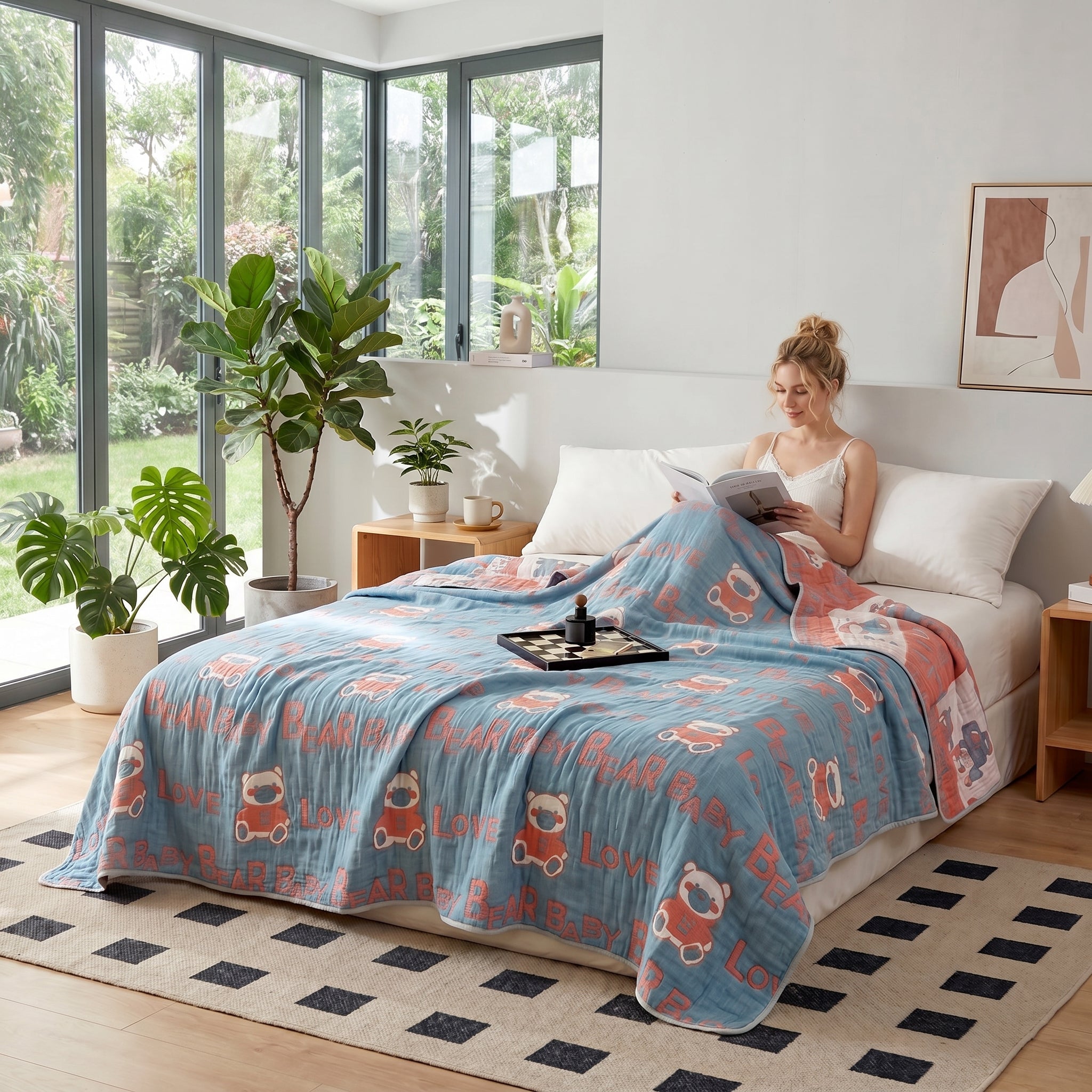 Woman relaxing in bed with a blue and peach 6-layer cotton gauze blanket featuring bear and "LOVE" patterns.