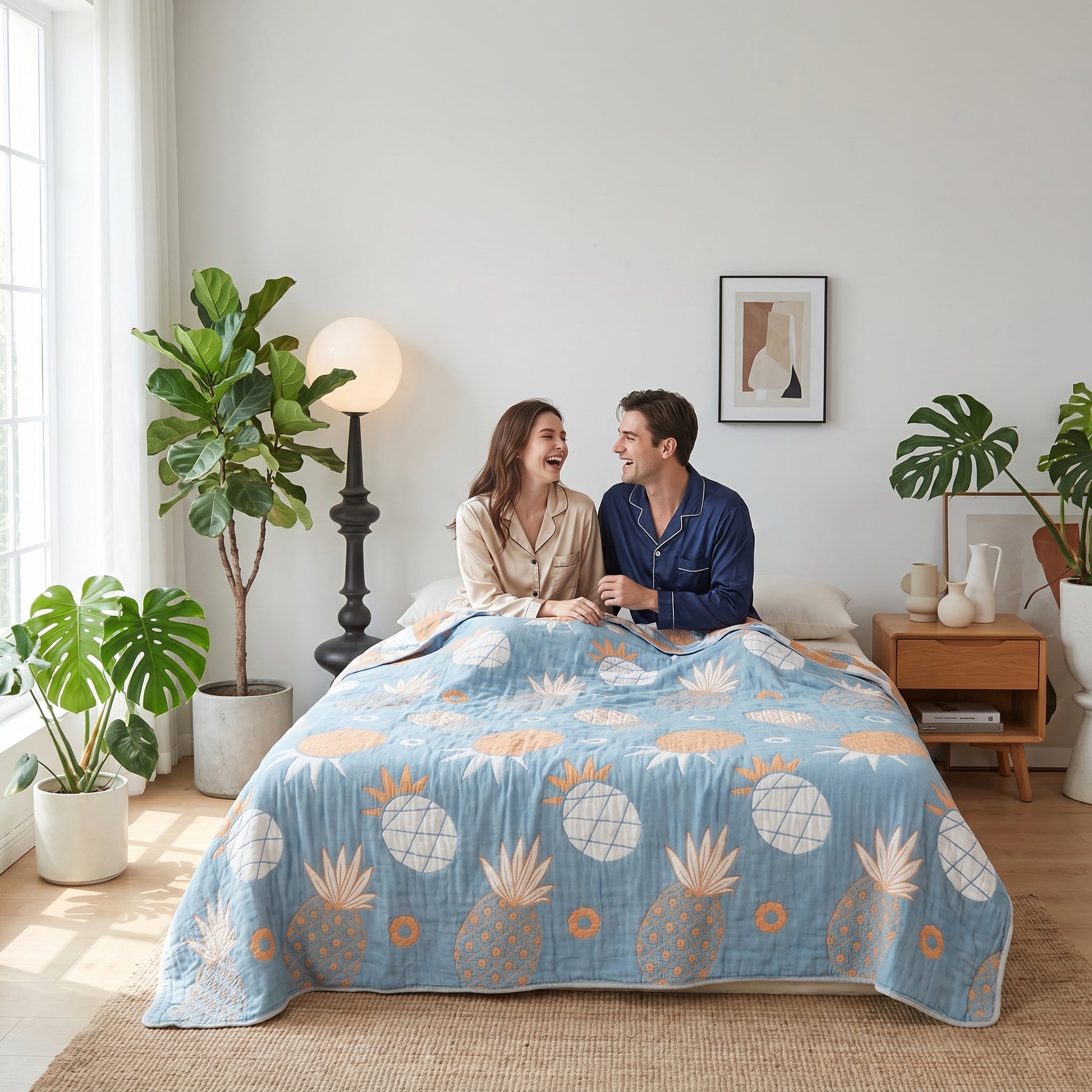 Couple laughing in bed under a blue 6-layer cotton gauze blanket with orange pineapple print.