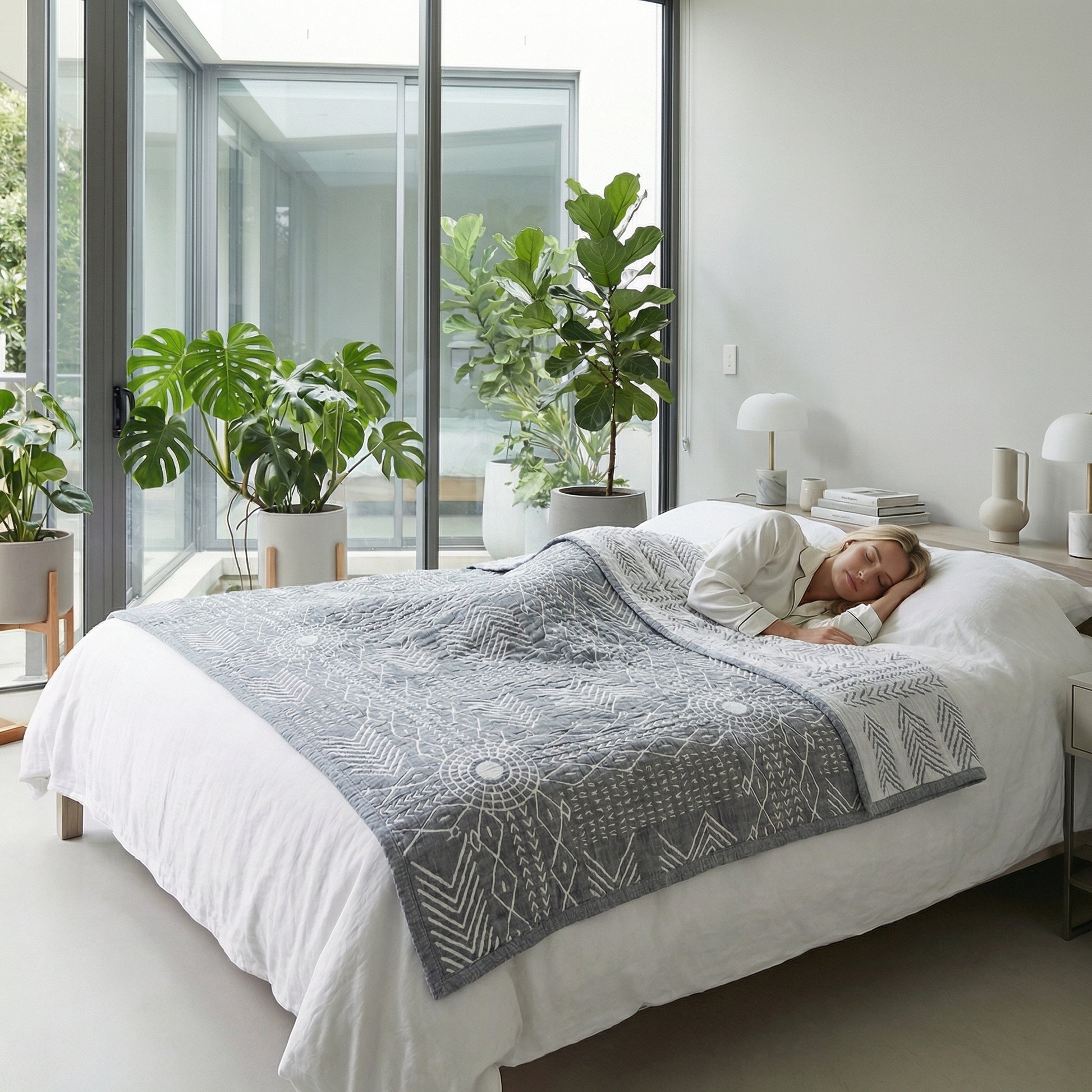 Woman sleeping peacefully under a gray three-layer gauze cotton towel blanket with white geometric patterns in a bright bedroom.