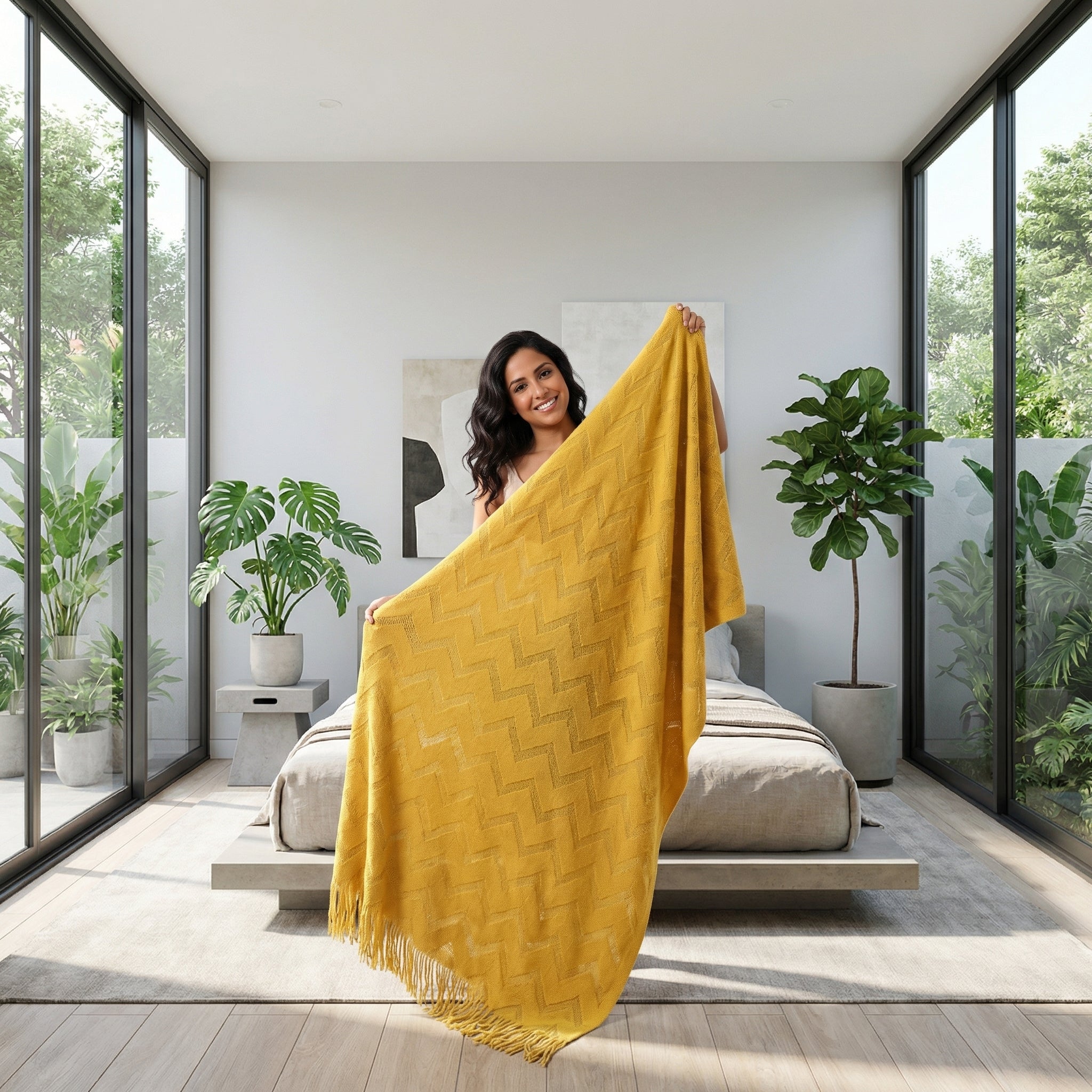 Smiling woman holding up a golden yellow acrylic throw blanket with a geometric jacquard pattern.