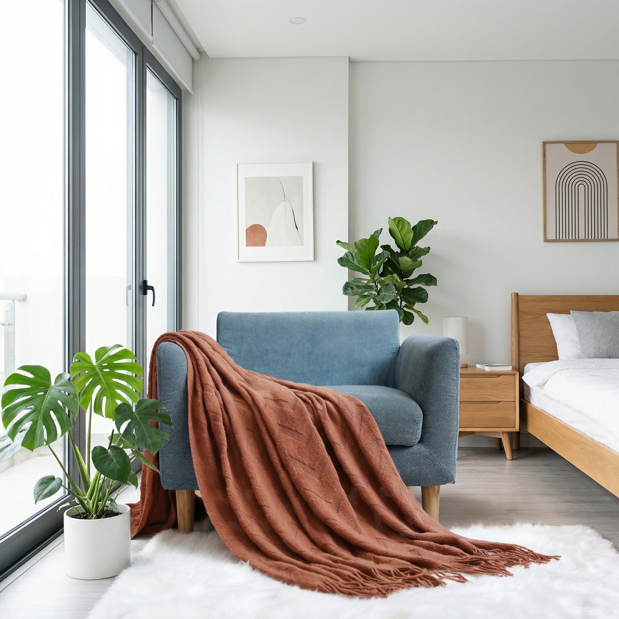 Terracotta geometric jacquard throw blanket draped over a blue armchair in a modern bedroom.