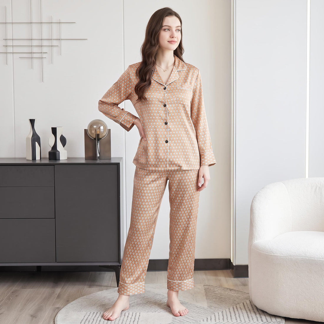 Woman wearing a tan geometric print mulberry silk pajama set with a button-up top and matching full-length pants.