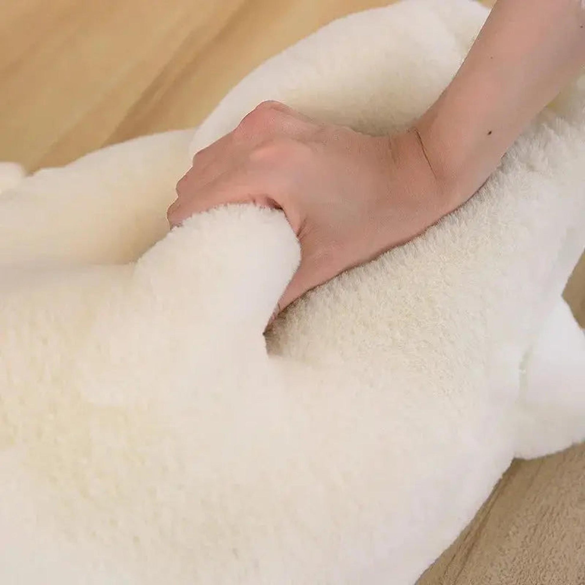 Hand squeezing a soft, fluffy white goose plush pillow toy to show its texture.