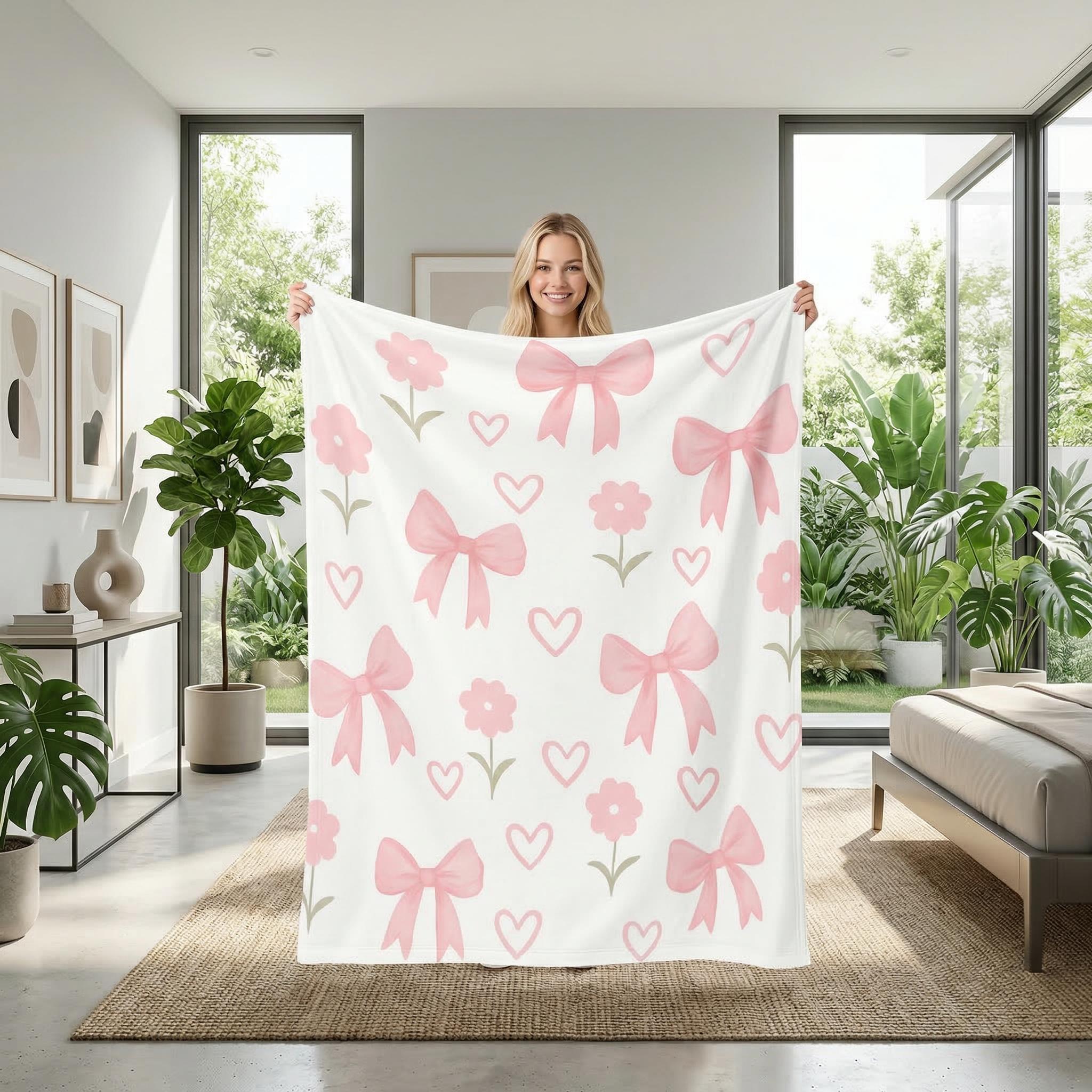 Smiling woman holding a white microfiber flannel blanket with pink bows, hearts, and flowers.