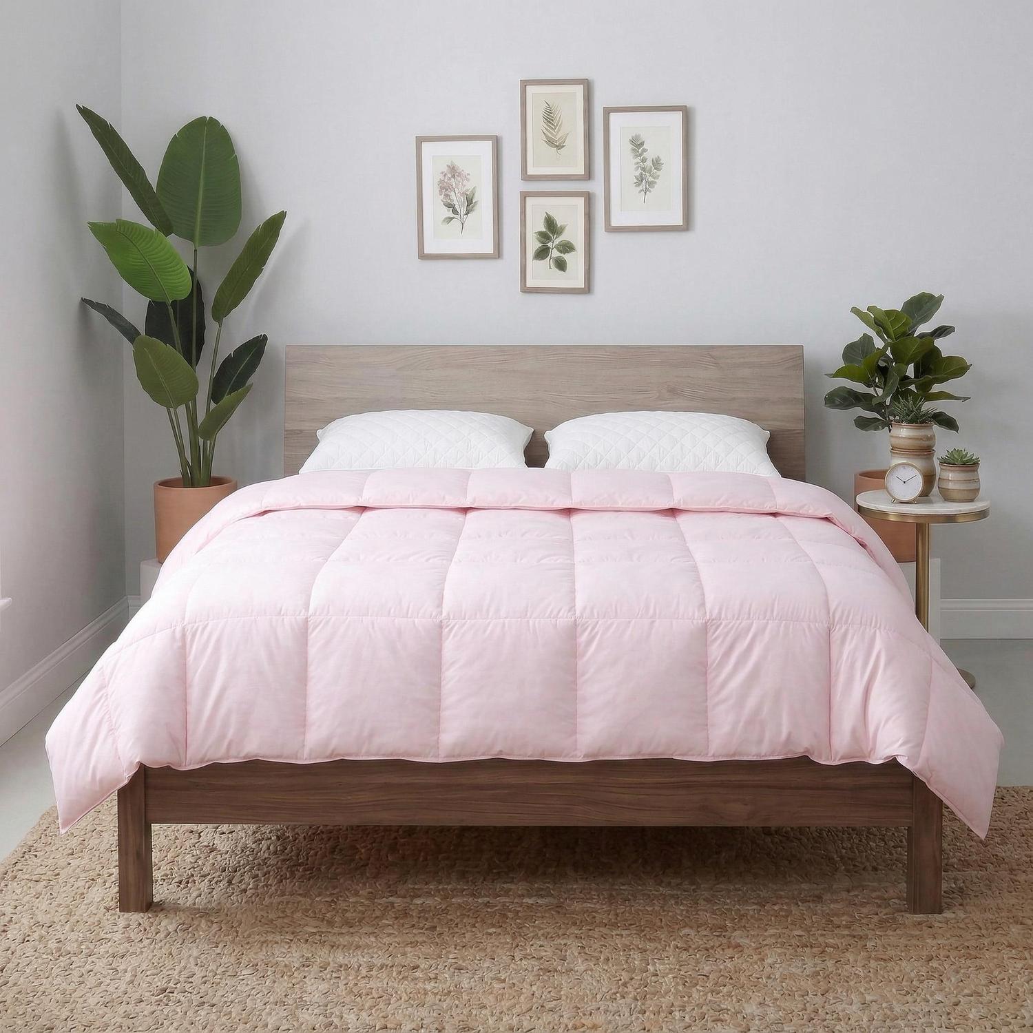 Pink hotel-style down comforter on a wooden bed, featuring box-stitched construction and two white pillows.