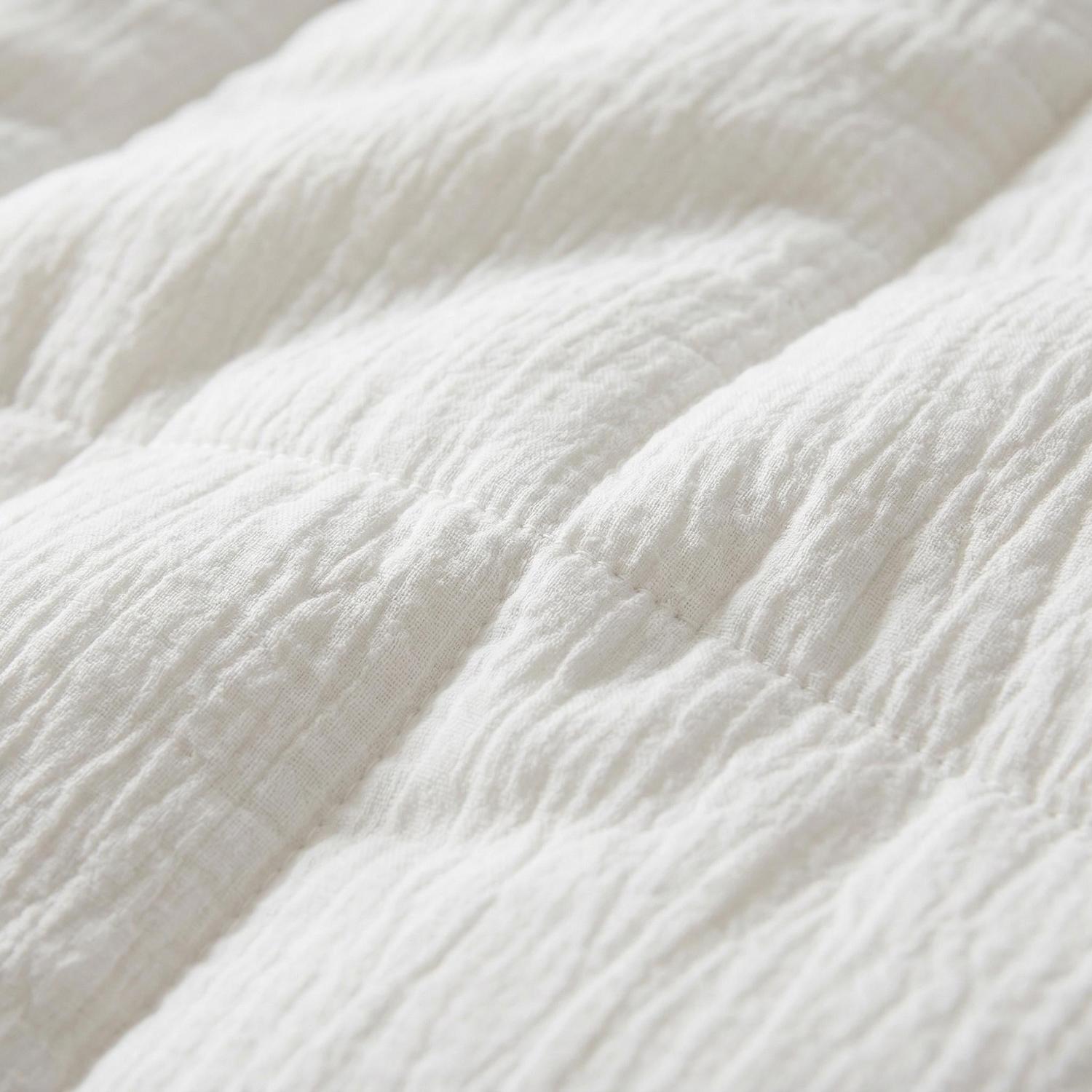 Close-up of a soft, white, quilted Japanese cotton comforter duvet insert with a crinkled texture.