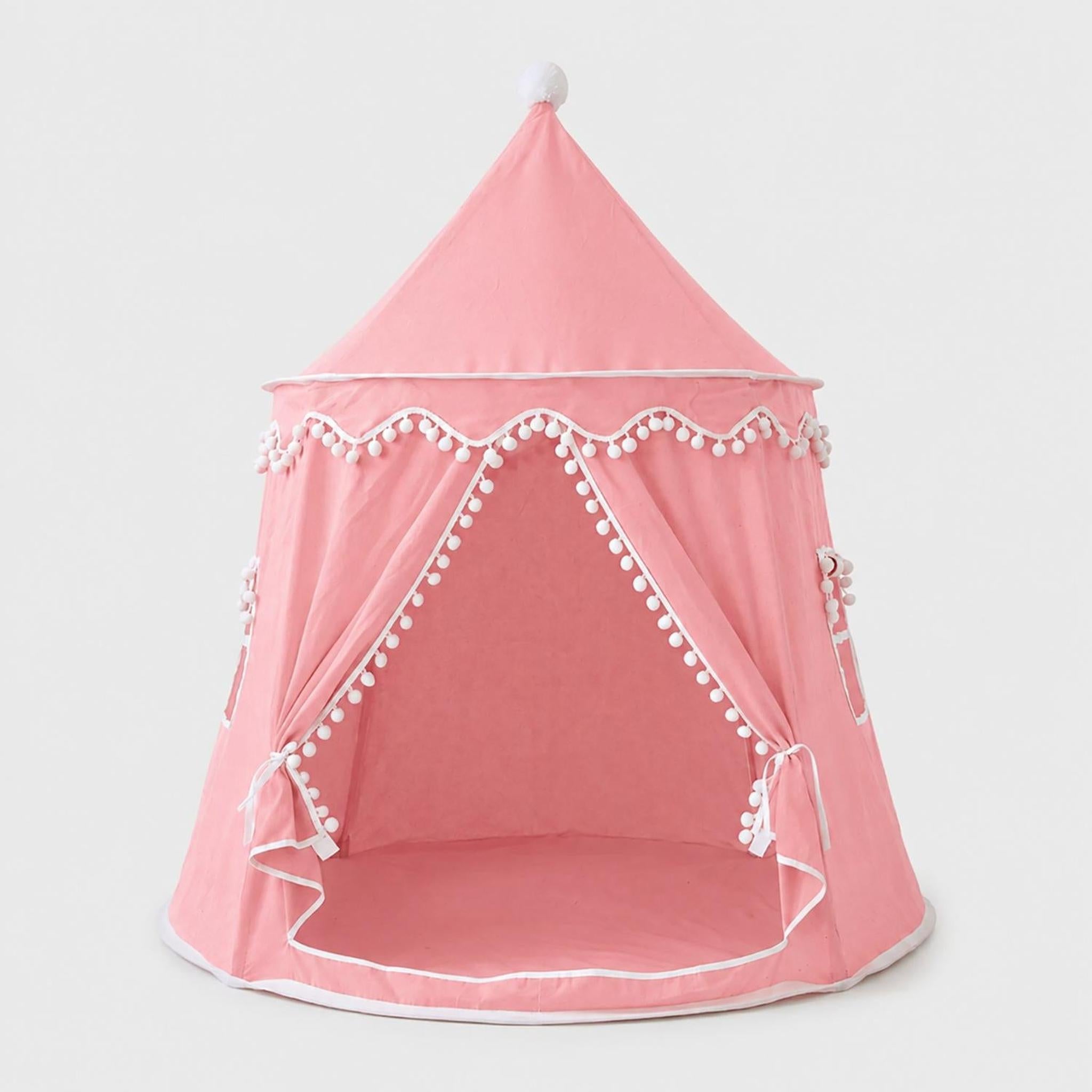 Pink fabric kids indoor play tent with white pom-pom trim and ties, featuring an open entrance.