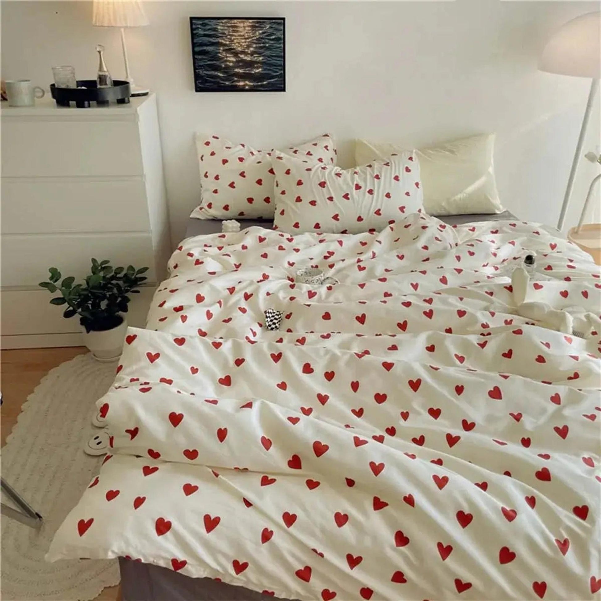 White microfiber bedding set with red heart pattern, including duvet cover and pillowcases, on a bed.