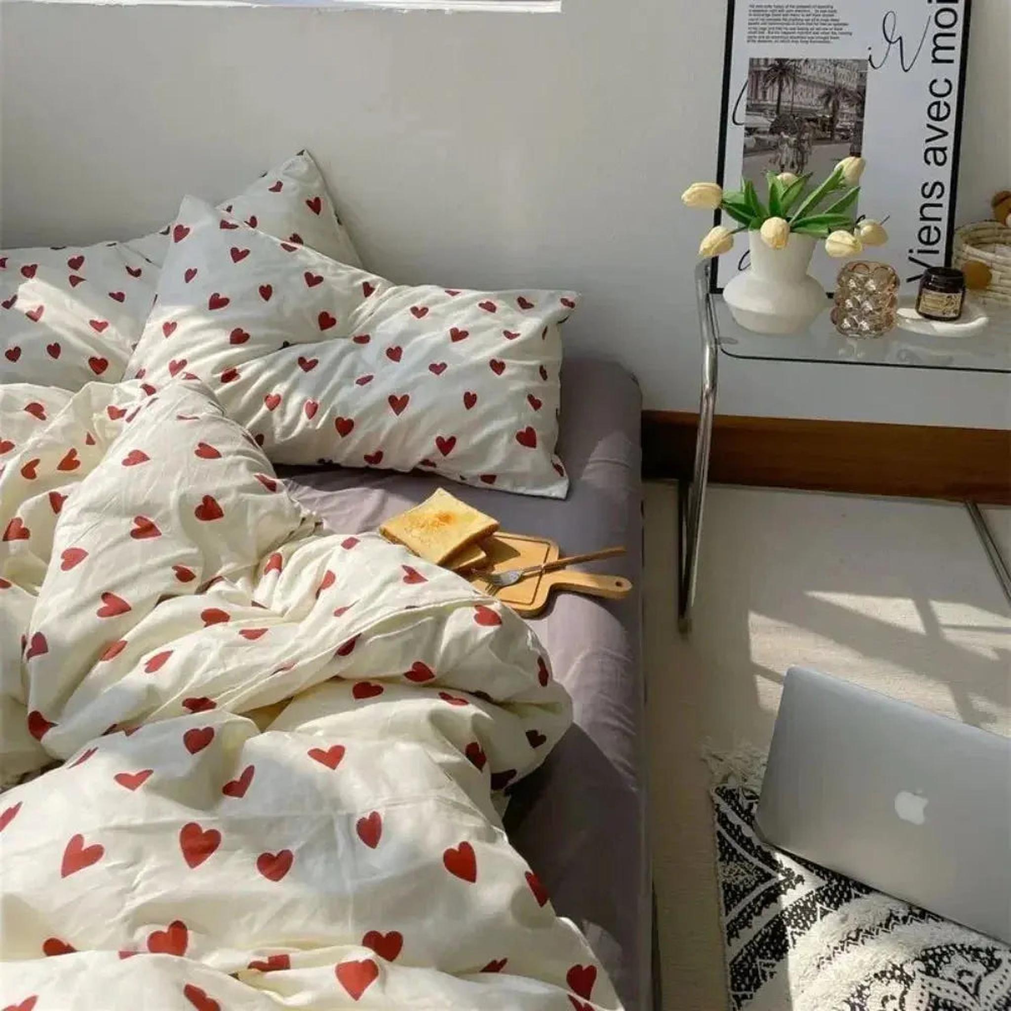 White microfiber bedding set with red heart pattern on a bed, featuring duvet cover and pillowcases.