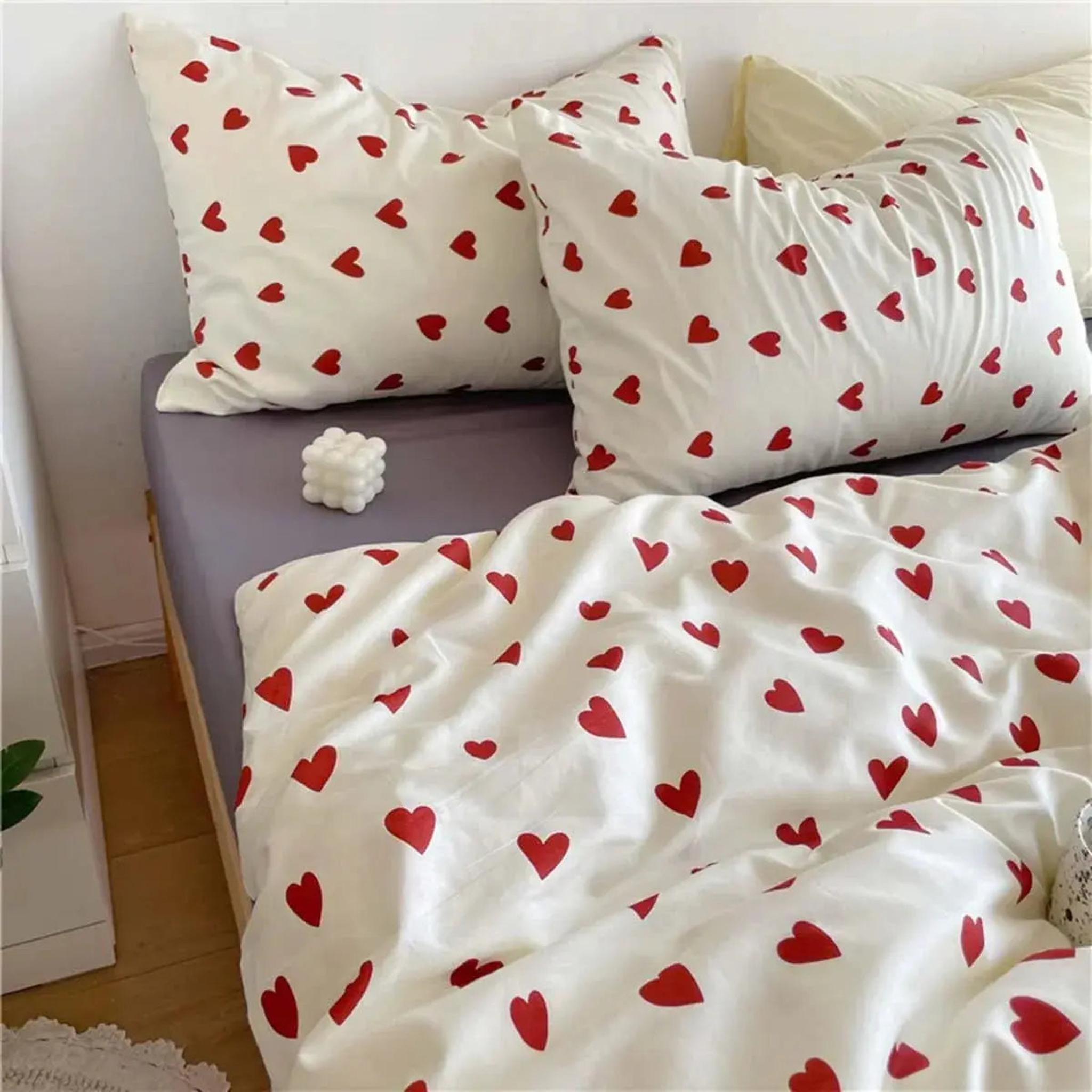 White microfiber bedding set with scattered red heart pattern on duvet cover and two pillowcases.