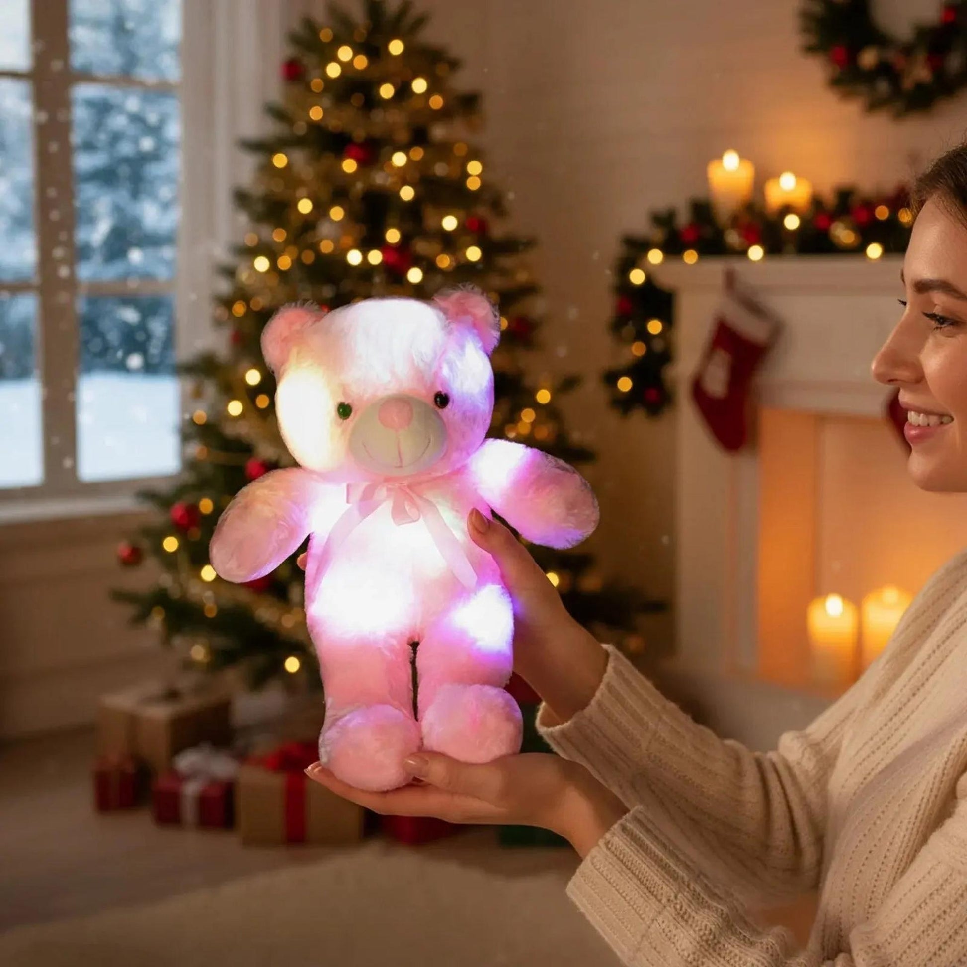 Woman holding a glowing pink plush teddy bear with color-changing LED lights in a festive room.