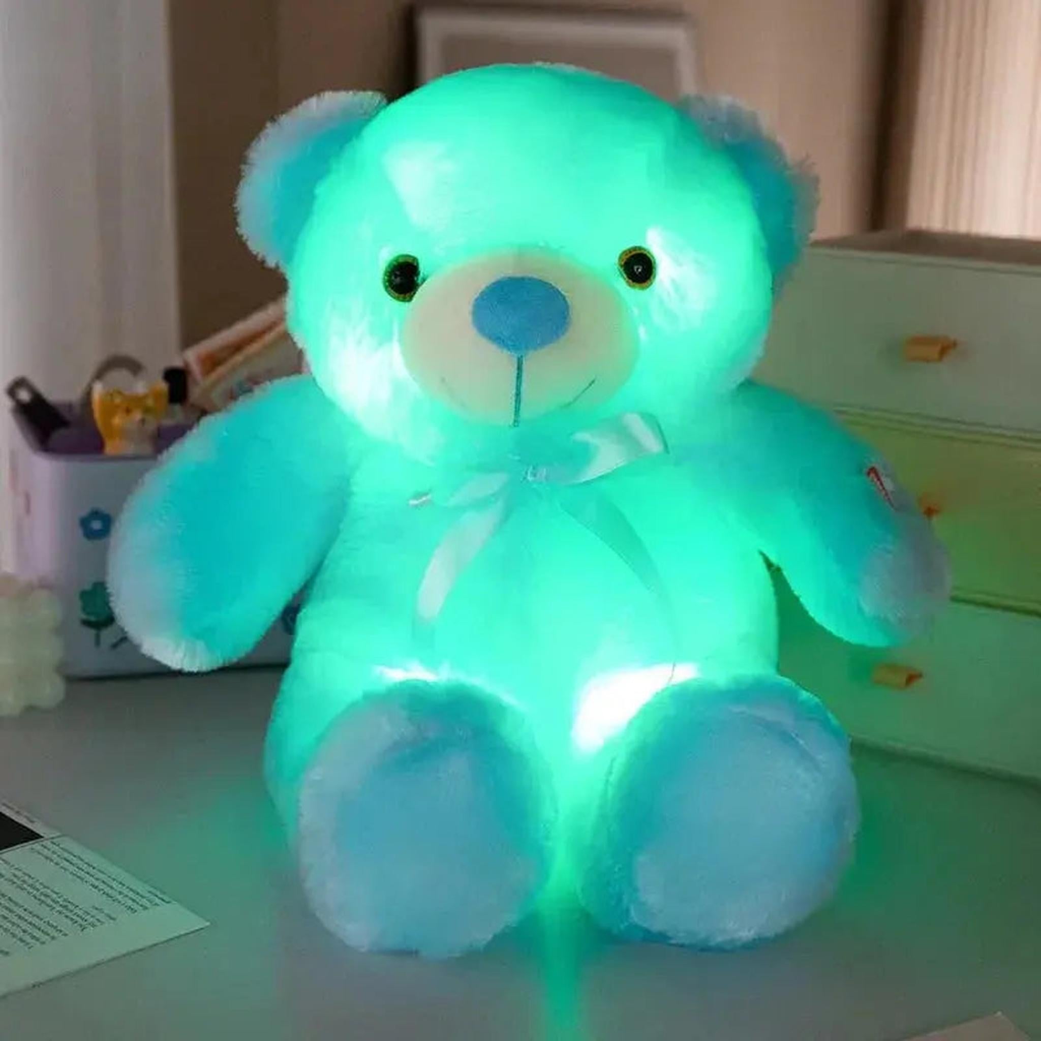 Soft plush teddy bear glowing with a vibrant, color-changing LED light, featuring blue accents and a bow.