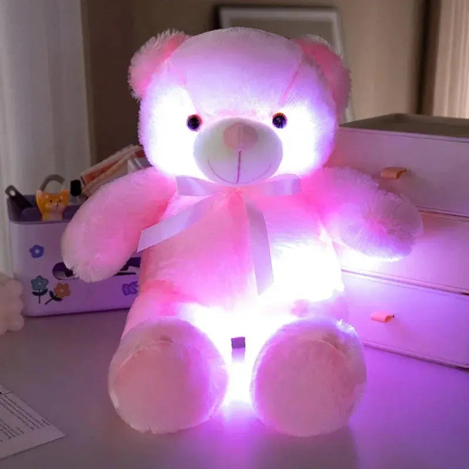 Pink plush teddy bear with a white bow, glowing with a soft, color-changing LED light.