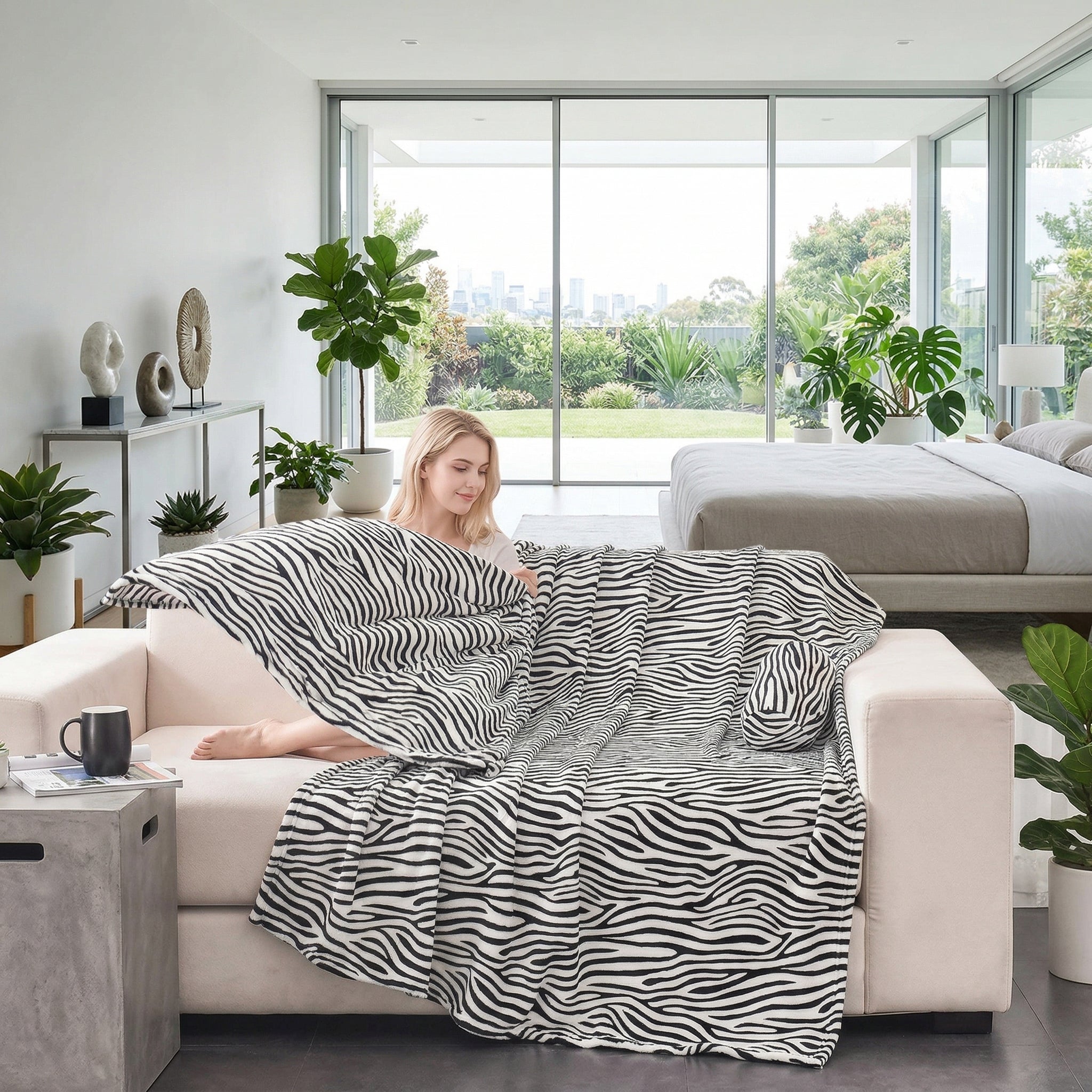Woman on a cream sofa with a black and white zebra print flannel blanket in a modern living room.
