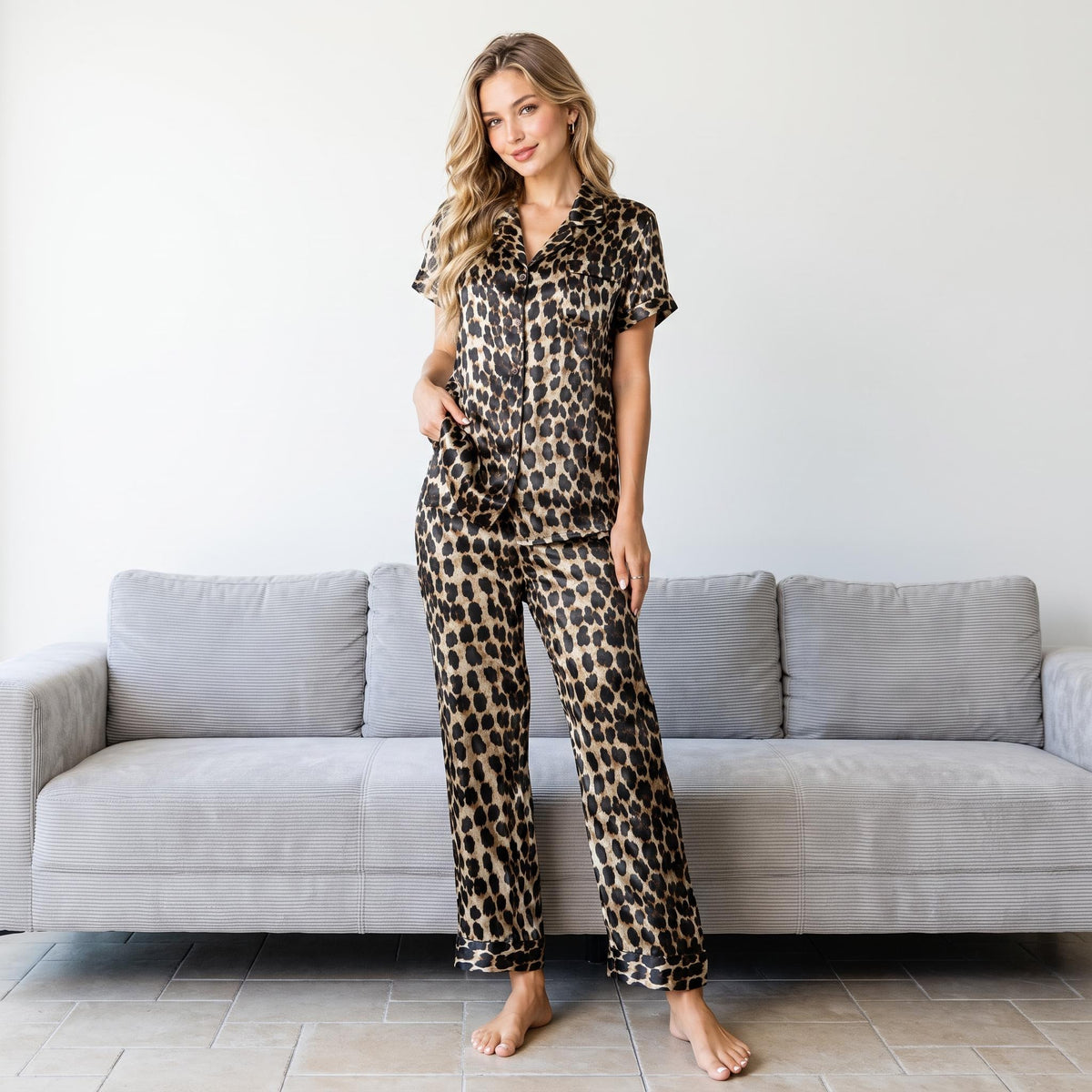 Woman wearing a luxurious leopard print silk pajama set with a short-sleeve button-down shirt and matching pants.