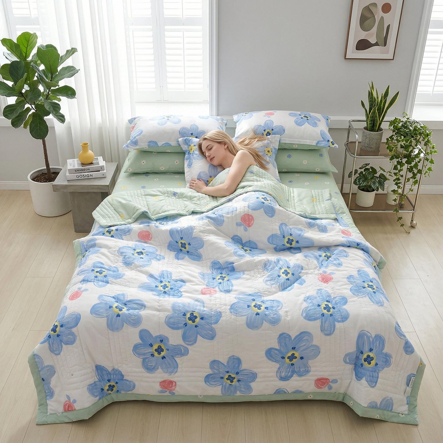 Woman sleeping under a white lightweight summer quilt with blue floral print and green trim.