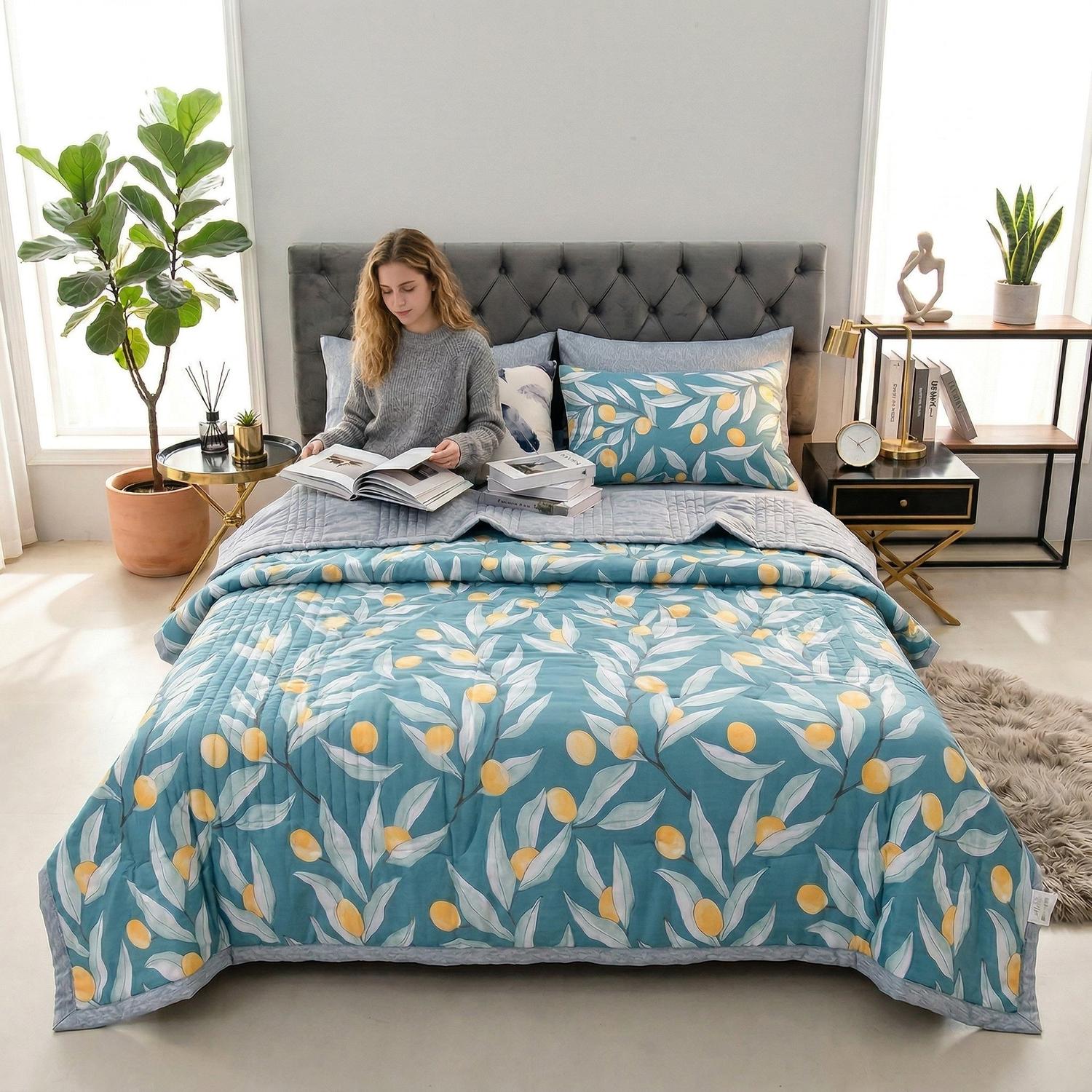 Blue lightweight summer quilt with yellow citrus and green leaf pattern on a queen bed.