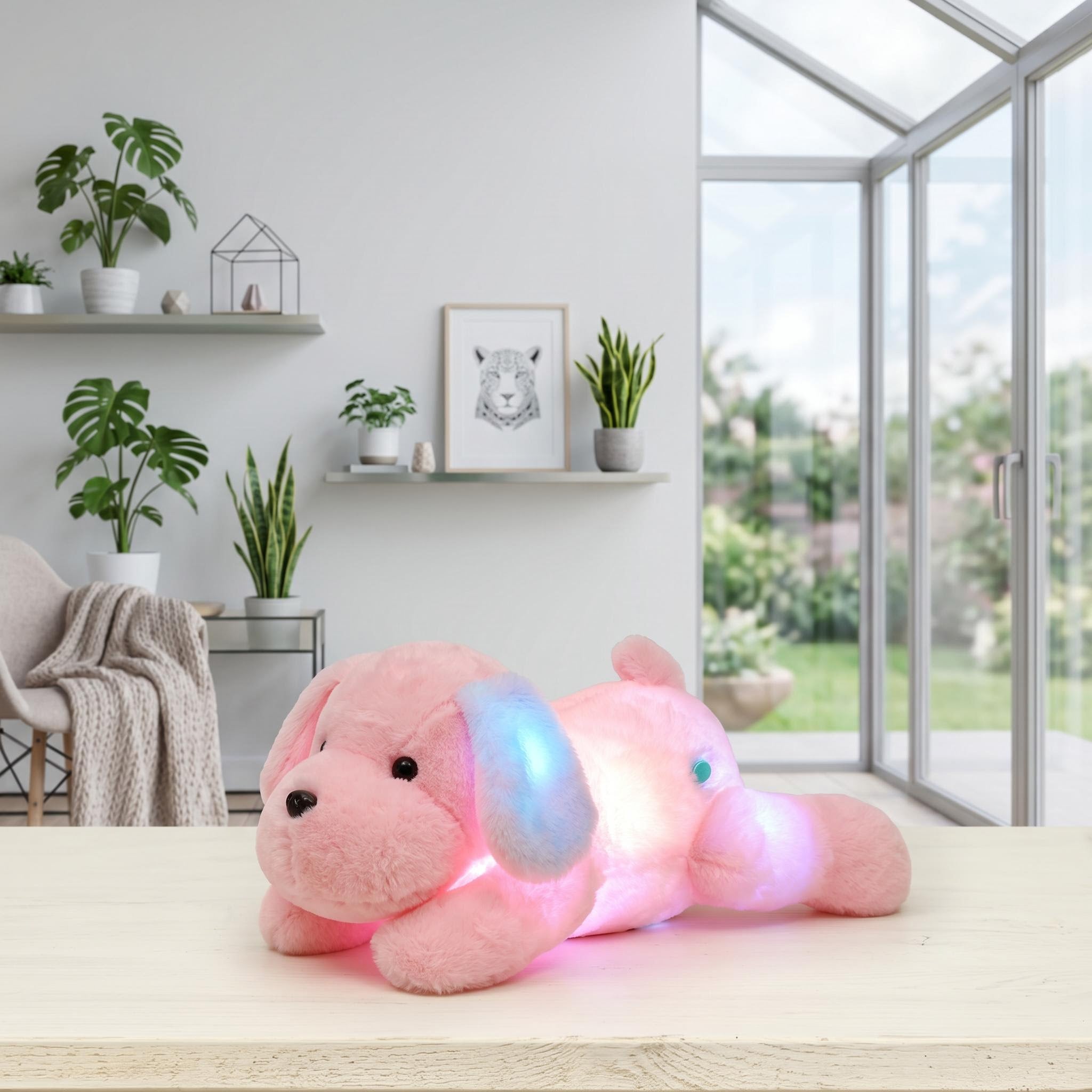Luminous pink plush dog pillow with glowing LED lights on a wooden table in a bright room.