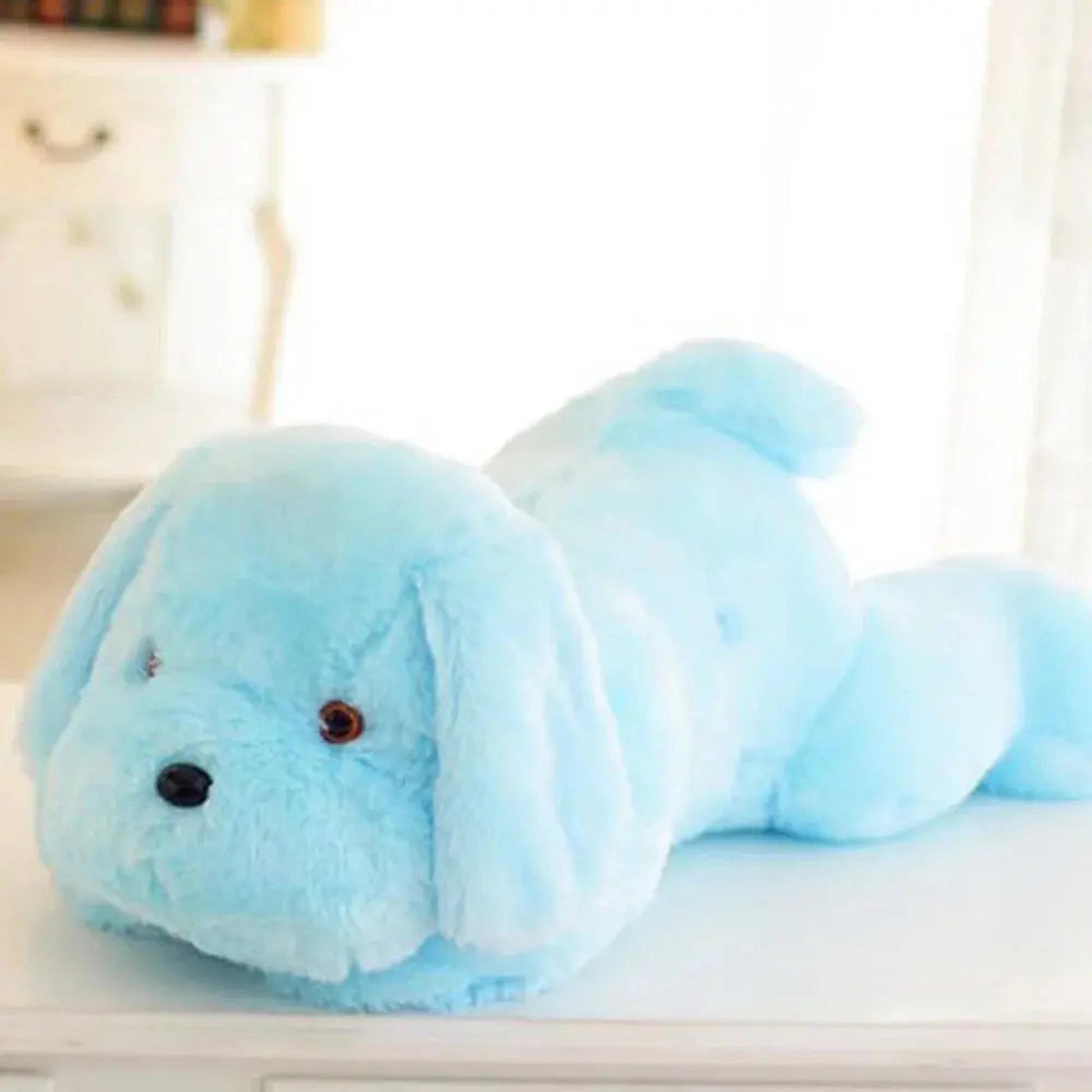 Light blue luminous dog plush pillow with a soft, glowing fabric lying on a white surface.