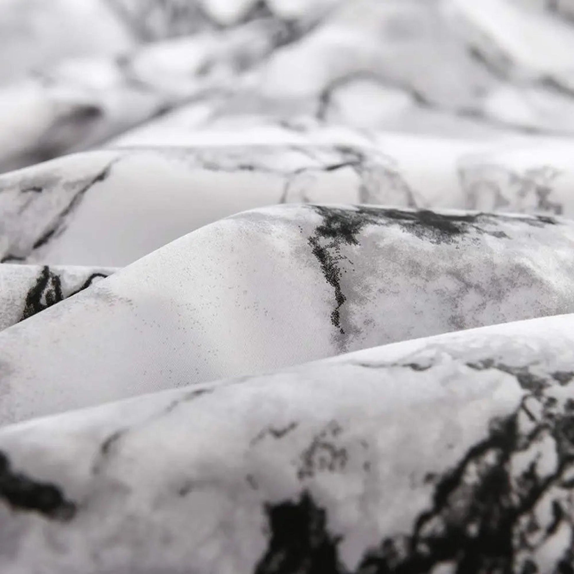 Close-up of a white microfiber fitted sheet with a stylish black and grey marble print.