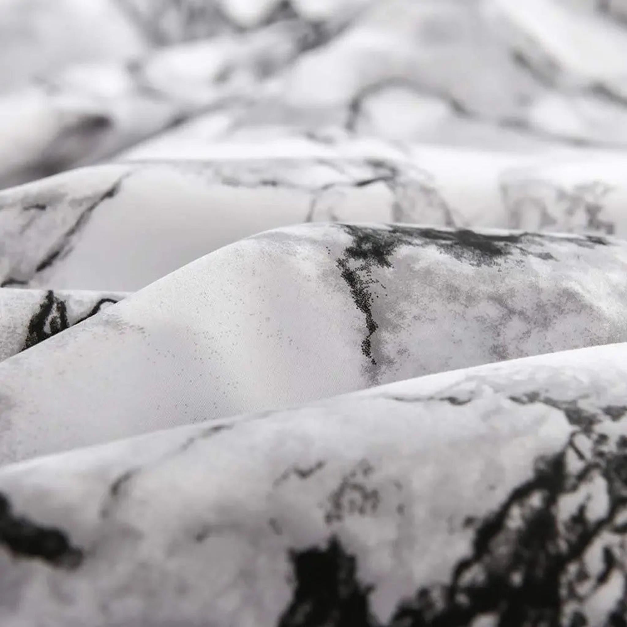 Close-up of a white microfiber fitted sheet with a stylish black and grey marble print.