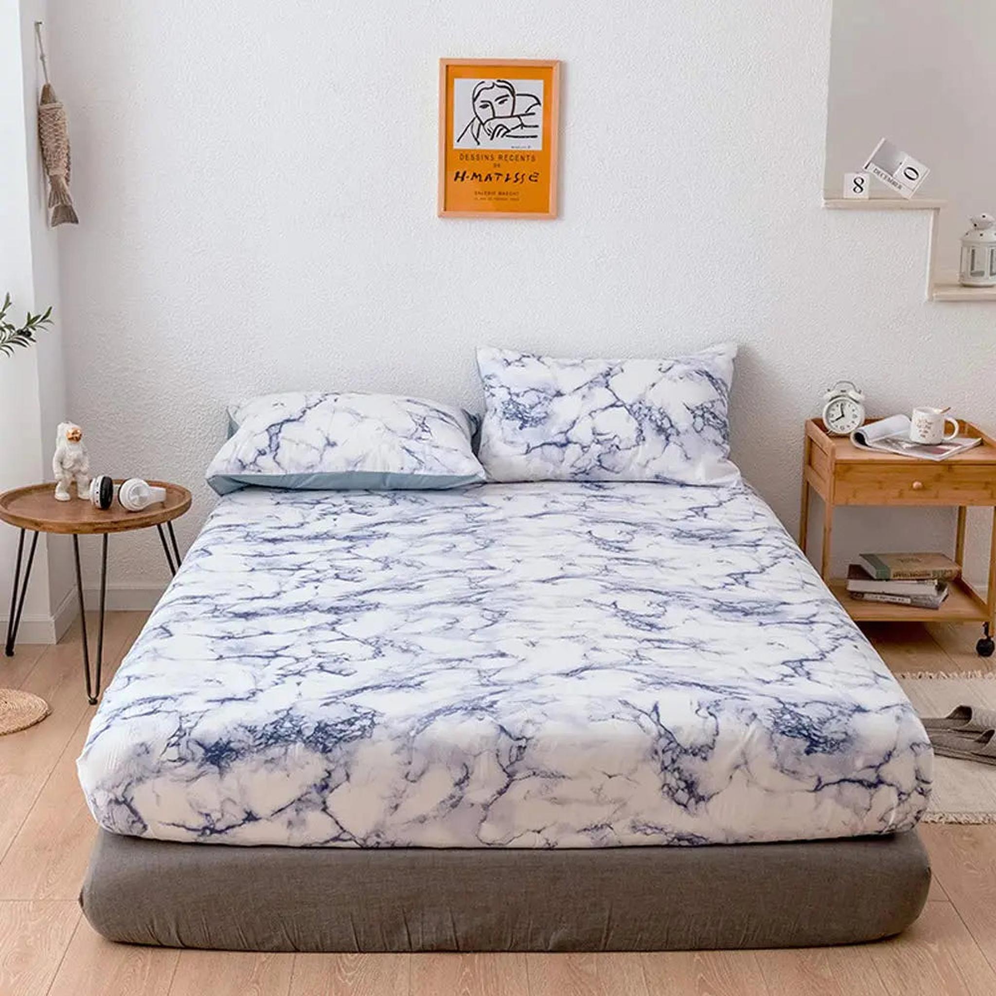 White microfiber fitted sheet with blue marble print, two matching pillowcases, on a bed in a modern bedroom.
