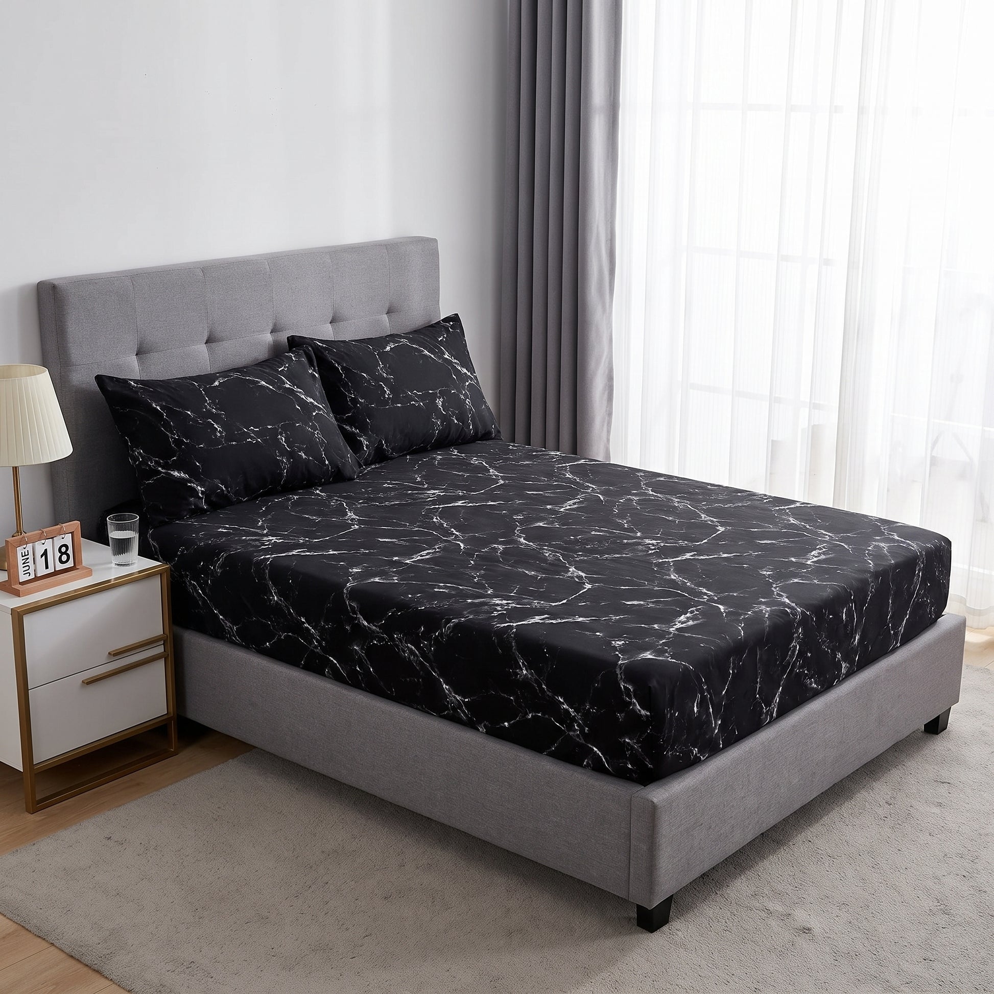 Black microfiber fitted sheet with white marble print on a bed with matching pillowcases.