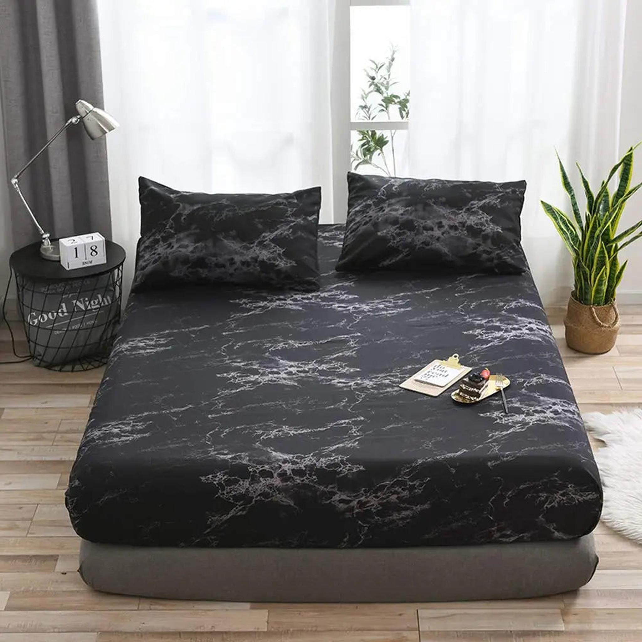 Black microfiber fitted sheet with a subtle grey marble print, styled on a bed with matching pillowcases.