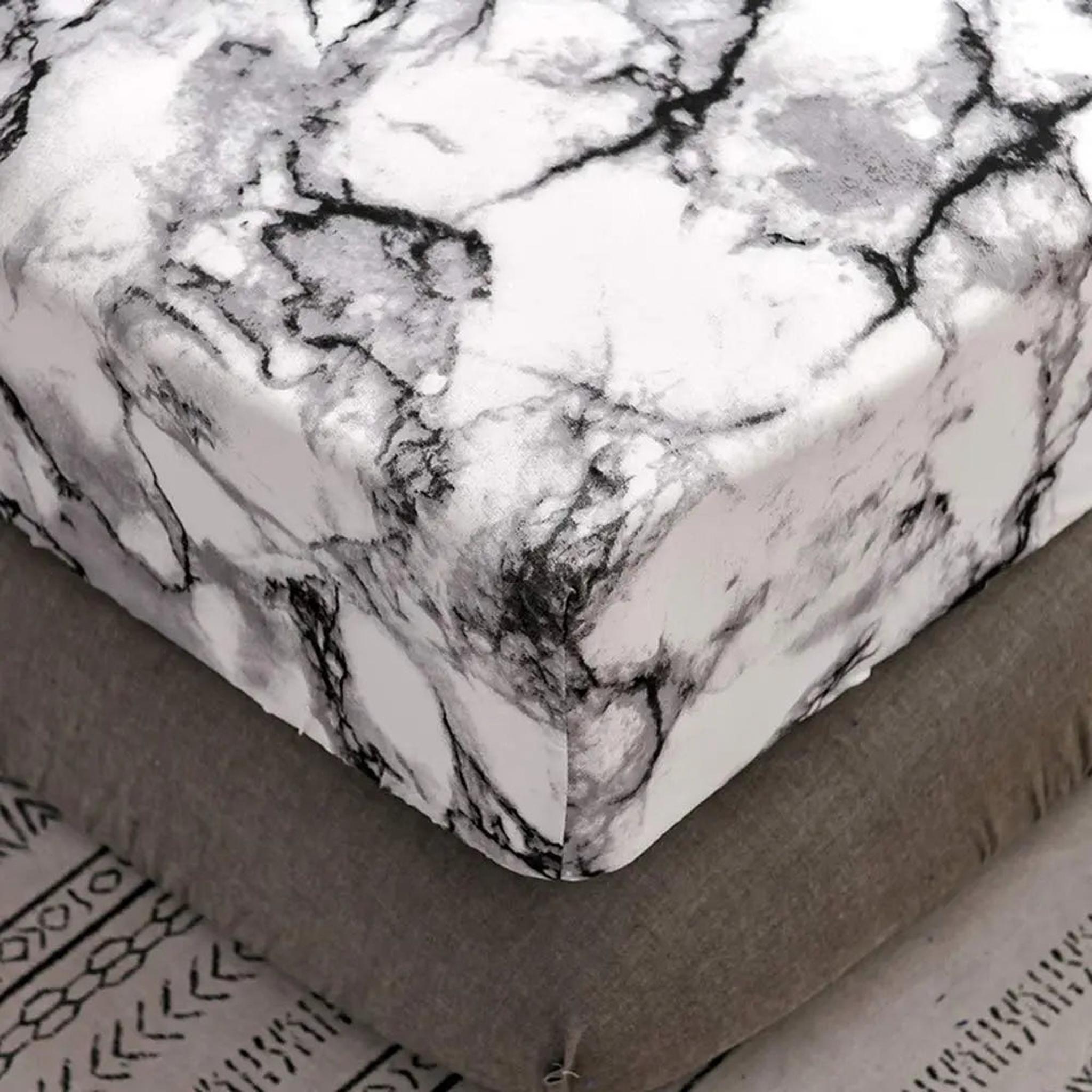 White microfiber fitted sheet with a striking black and gray marble print, securely fitted on a mattress.