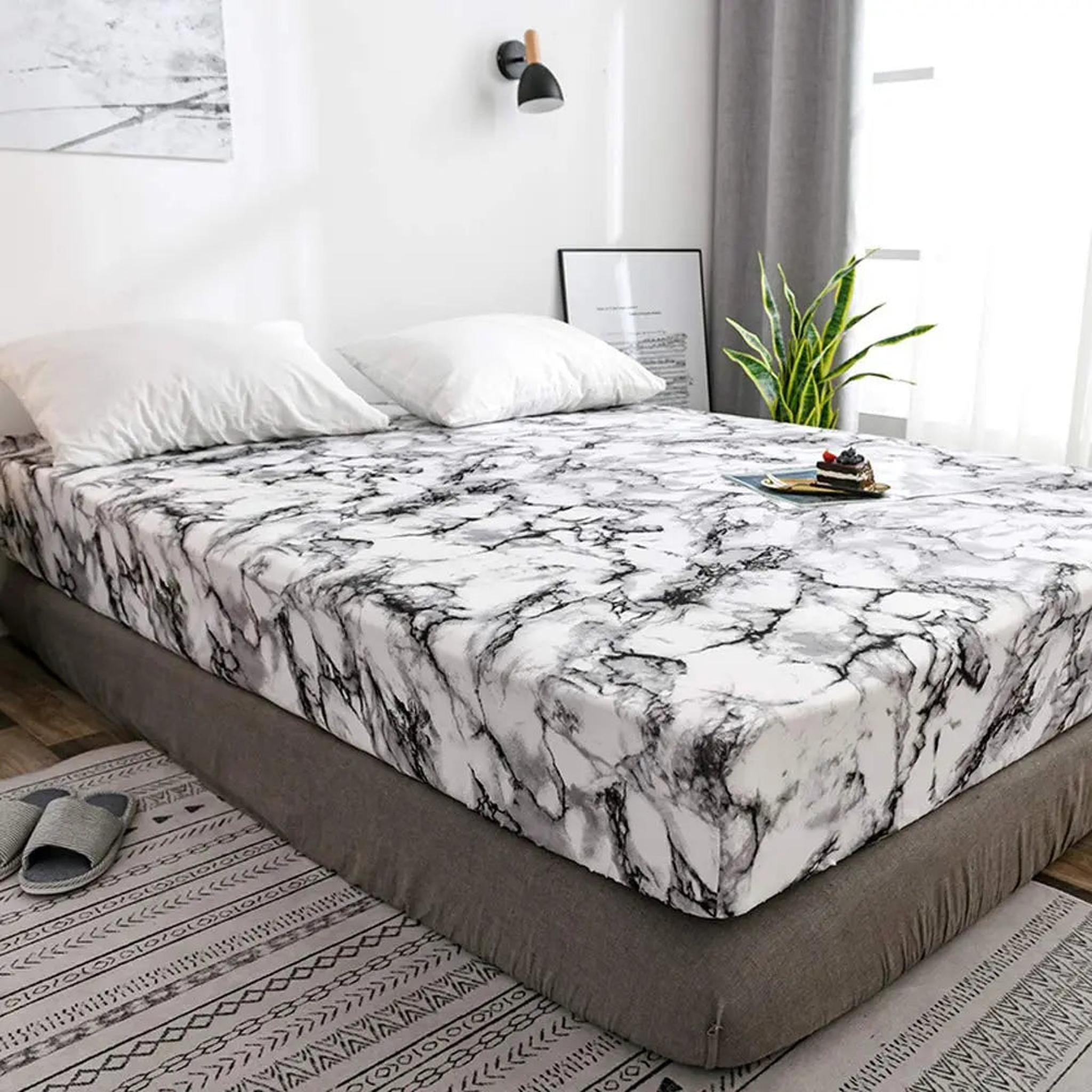 White and black marble print microfiber fitted sheet on a bed with white pillows.