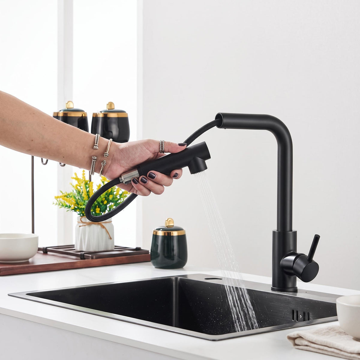 Matte black stainless steel pull-out kitchen faucet with a flexible hose and dual spray mode over a modern sink.