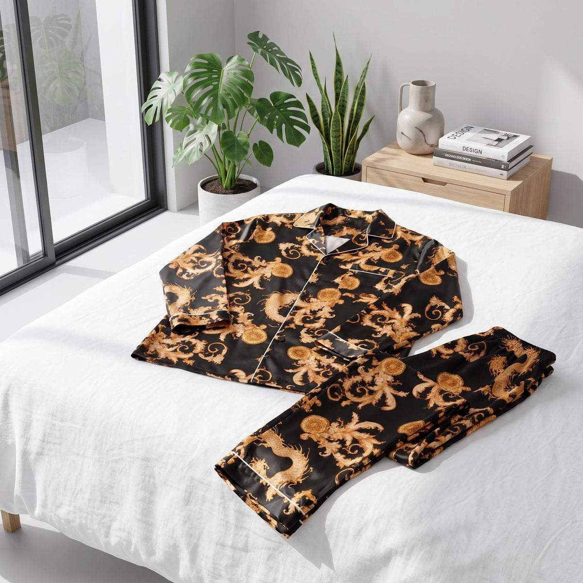 Men's black silk pajama set with a gold dragon print, featuring a notch collar and button-down top on a white bed.