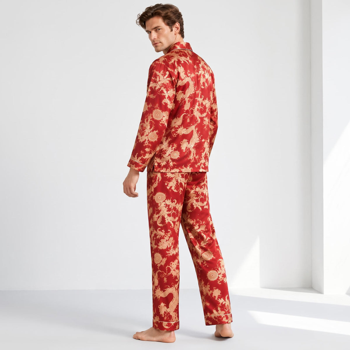 Man wearing a red mulberry silk pajama set with a gold dragon print, notch collar, and long sleeves in a relaxed fit.
