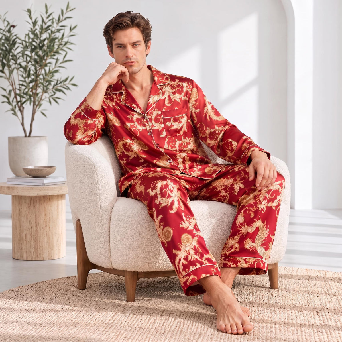 Man wearing a red mulberry silk pajama set with a gold dragon print, notch collar, and button-down design, sitting in a chair.