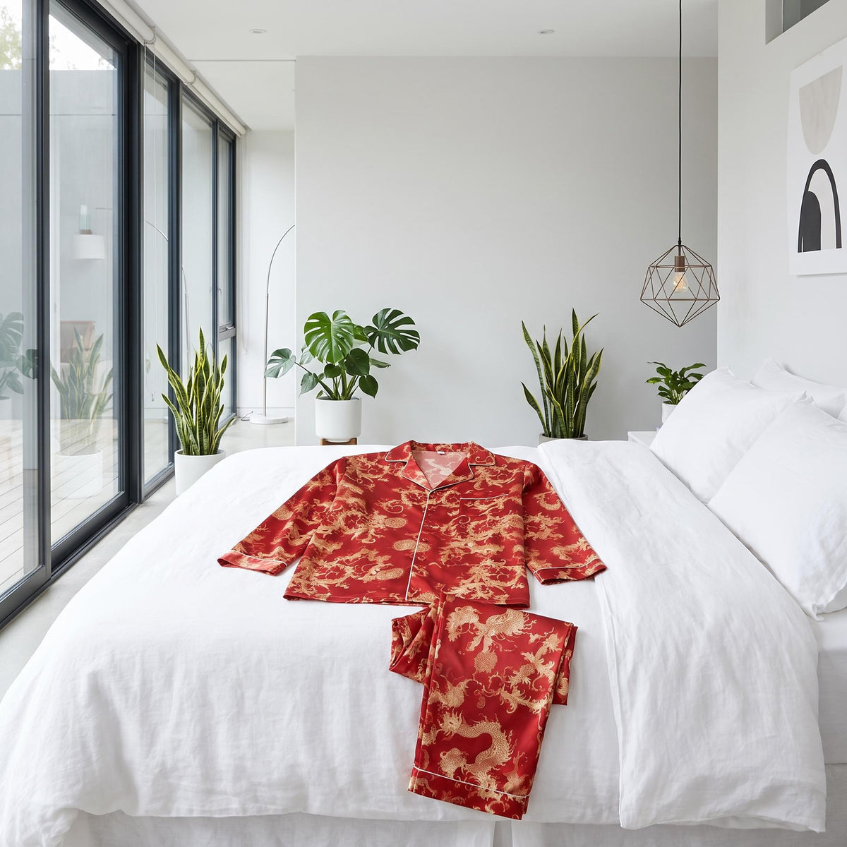 Red silk men's pajama set with gold dragon print, featuring a notch collar and button-down top, laid flat on a white bed.
