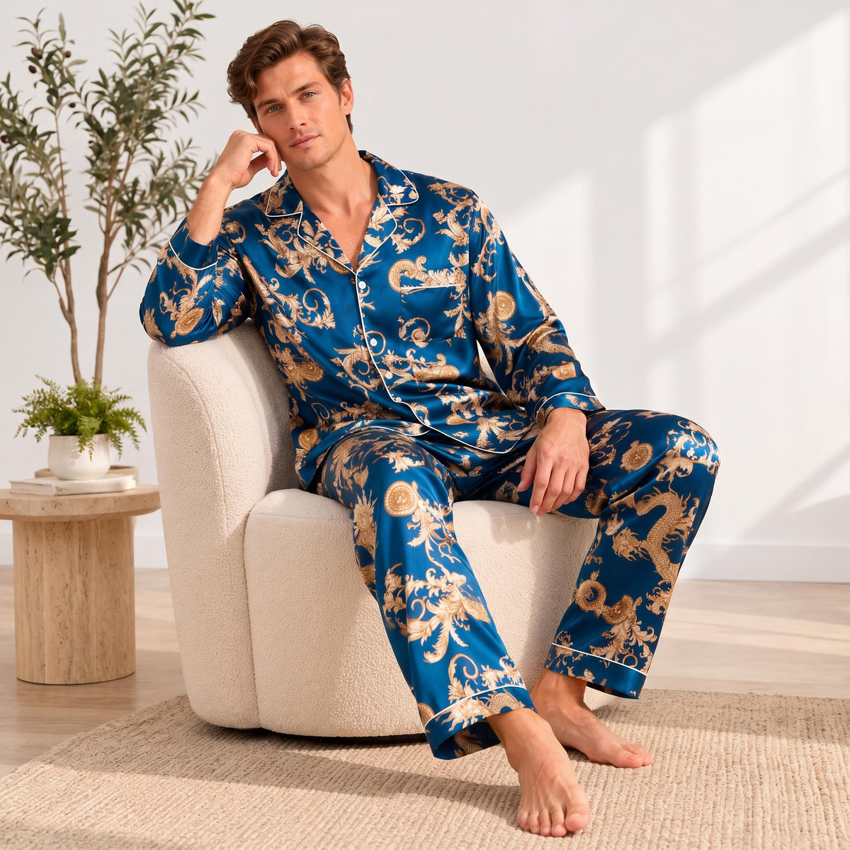Man wearing a blue mulberry silk pajama set with a gold dragon print, notch collar, and button-down front while sitting.