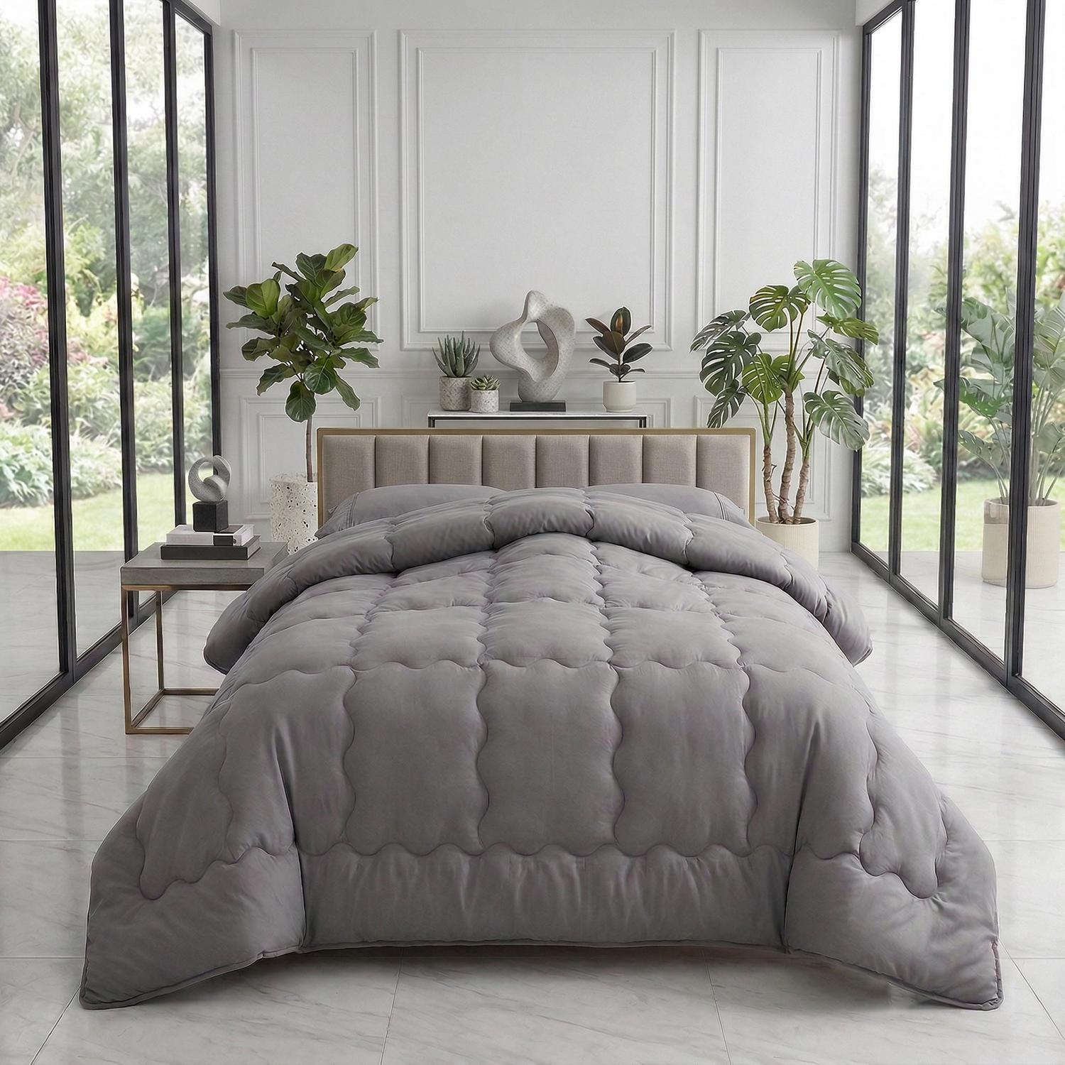 Minimalist solid gray quilt comforter with scalloped stitching on a bed in a modern room.