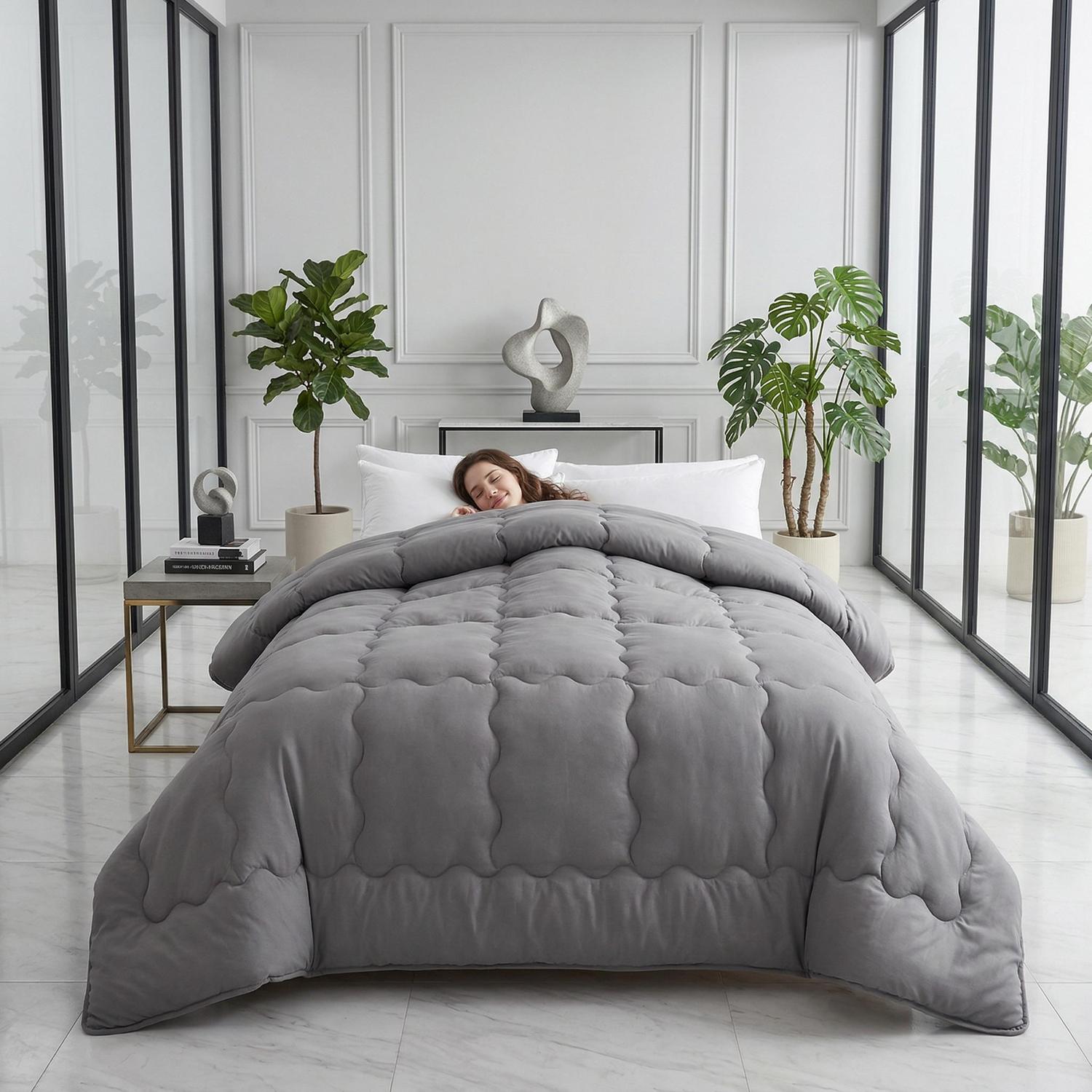 Woman sleeping peacefully under a gray minimalist solid color quilt comforter in a modern bedroom.