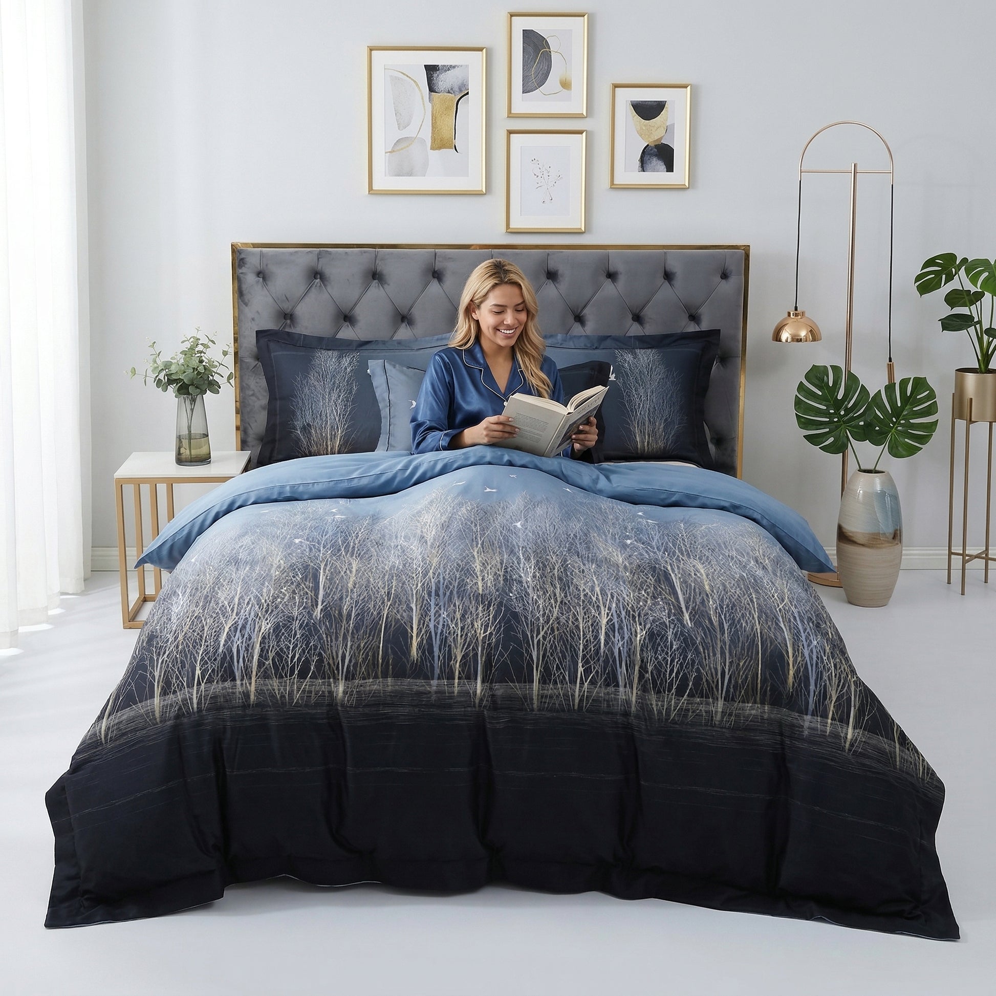 Woman reading in a bed with a dark blue Nature Inspired Mosaic Duvet Cover Bedding Set featuring a white tree design.