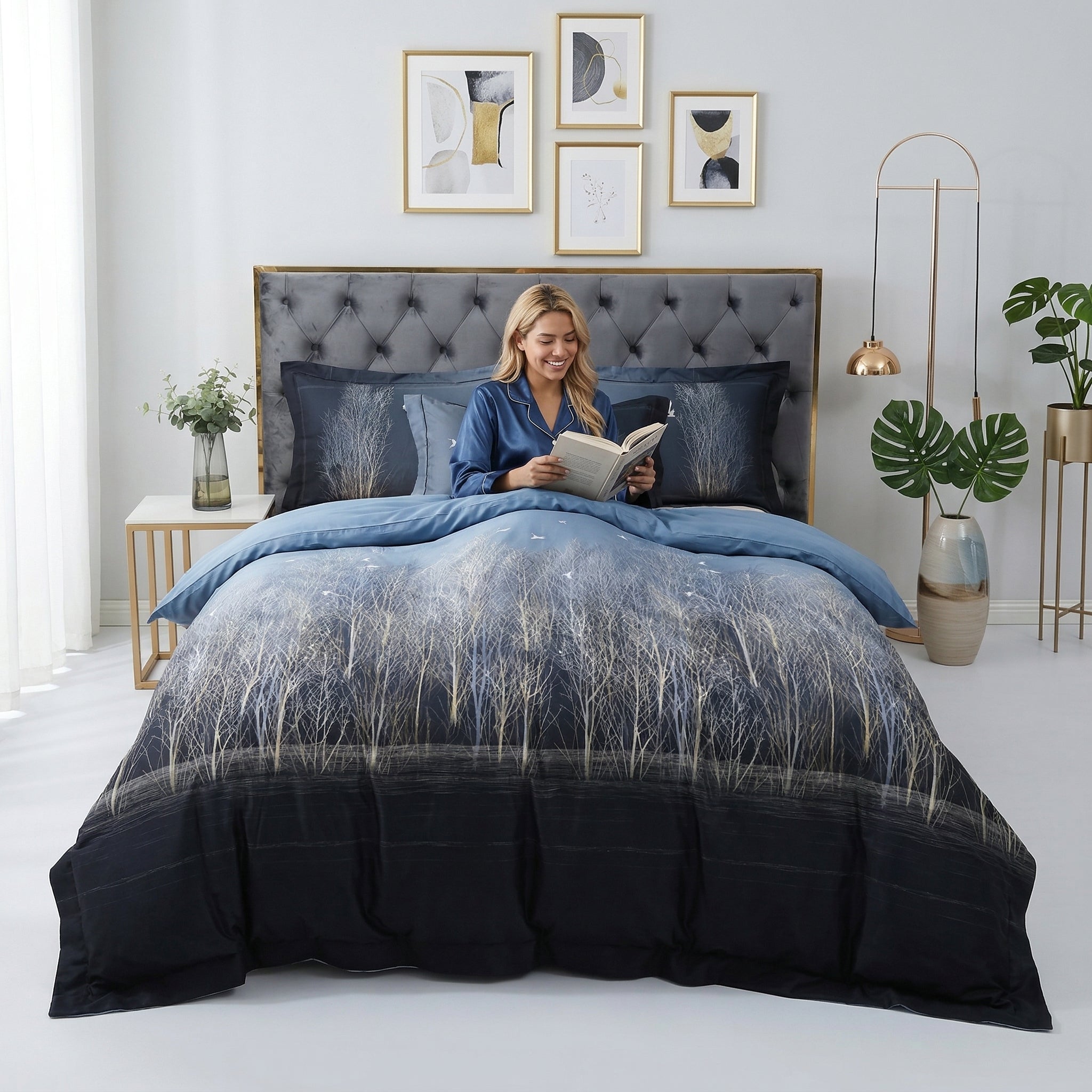 Woman reading in a bed with a dark blue Nature Inspired Mosaic Duvet Cover Bedding Set featuring a white tree design.