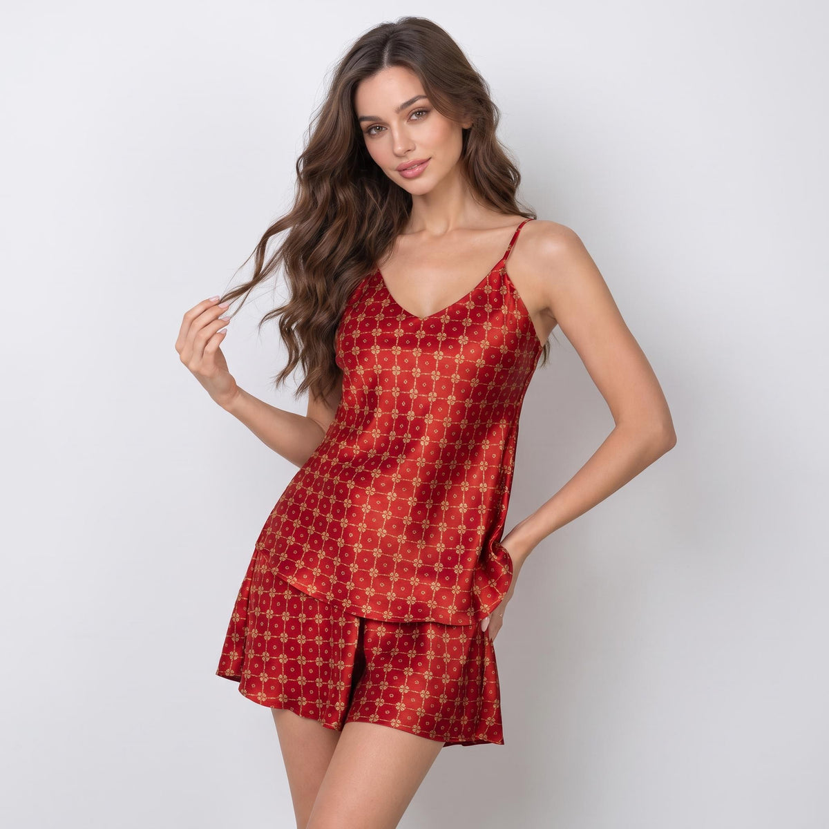 Red silk pajama set with V-neck camisole and shorts featuring a gold geometric pattern and adjustable straps.
