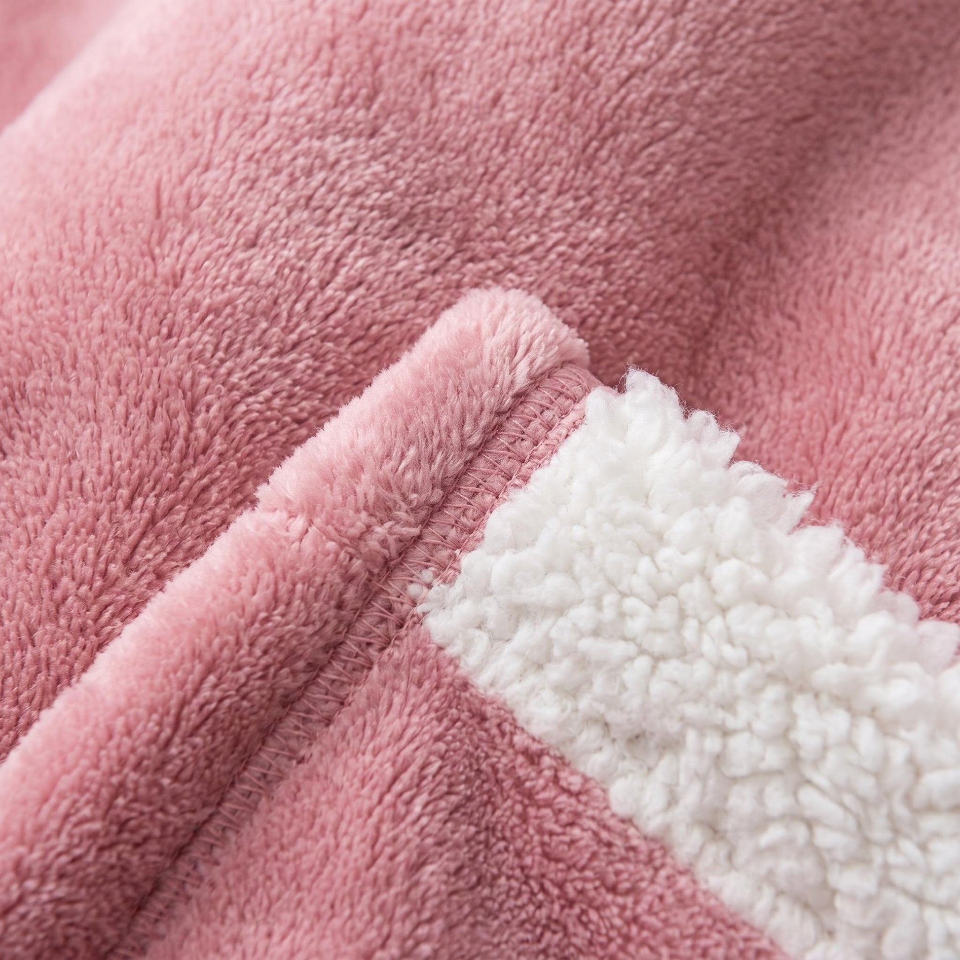 Close-up of a soft, pink polyester flannel oversized hooded blanket with a white sherpa lining.