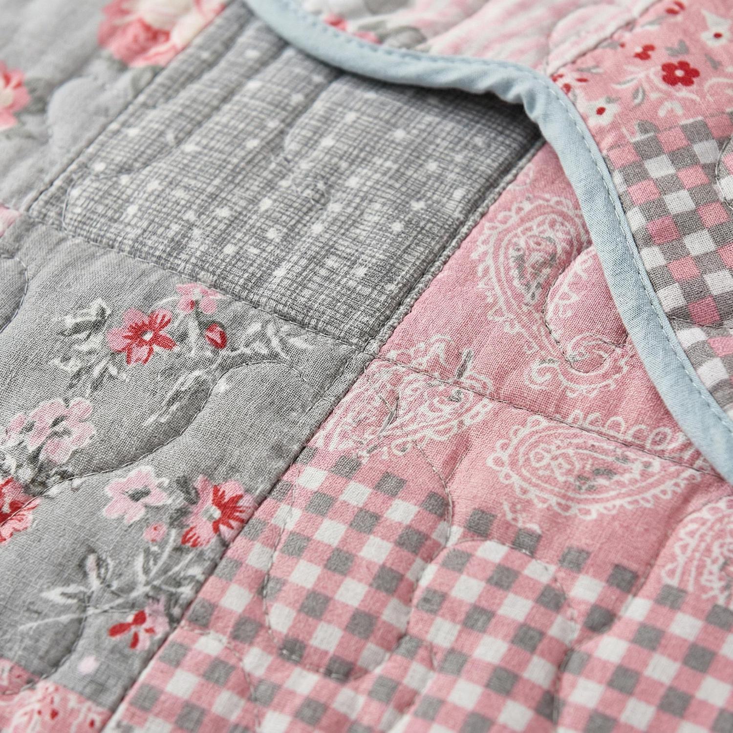Pink flowers printed quilt set with two pillowcases on a bed.