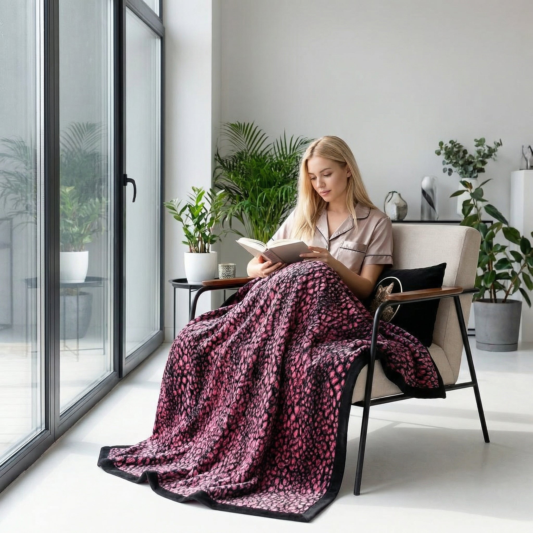 Blonde woman reading, cozy under a soft pink leopard print plush blanket in a modern living room.