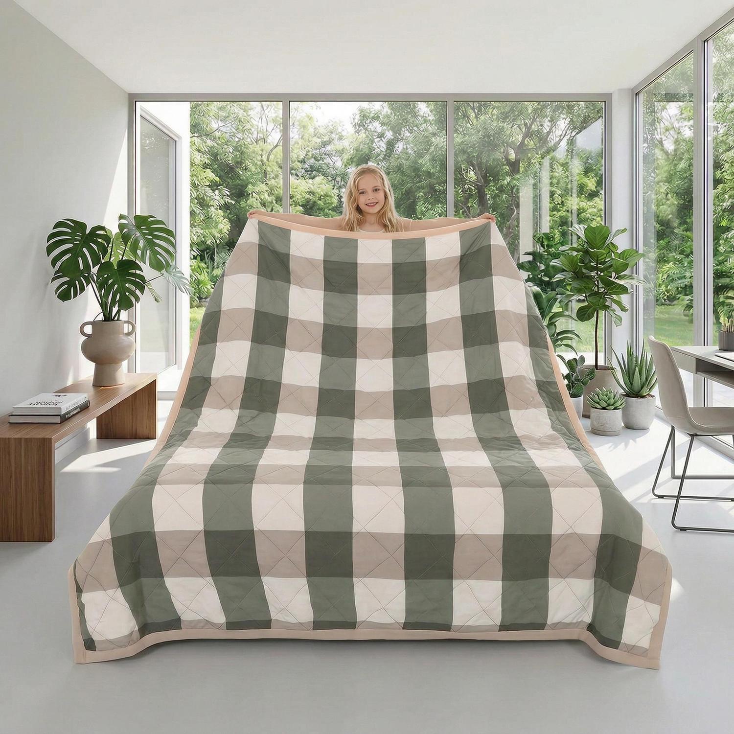 Lightweight plaid summer quilt in green, beige, and white, held by a person in a bright room.