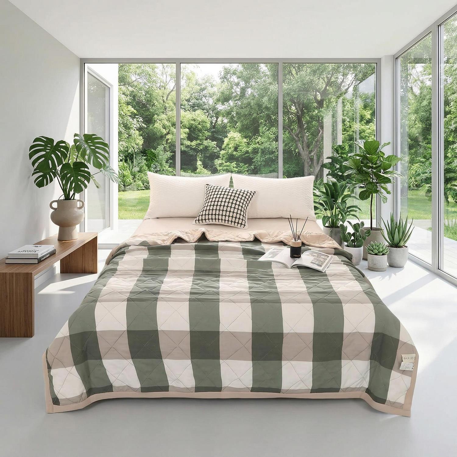 Green and beige plaid lightweight polyester summer quilt on a bed in a bright room with large windows.