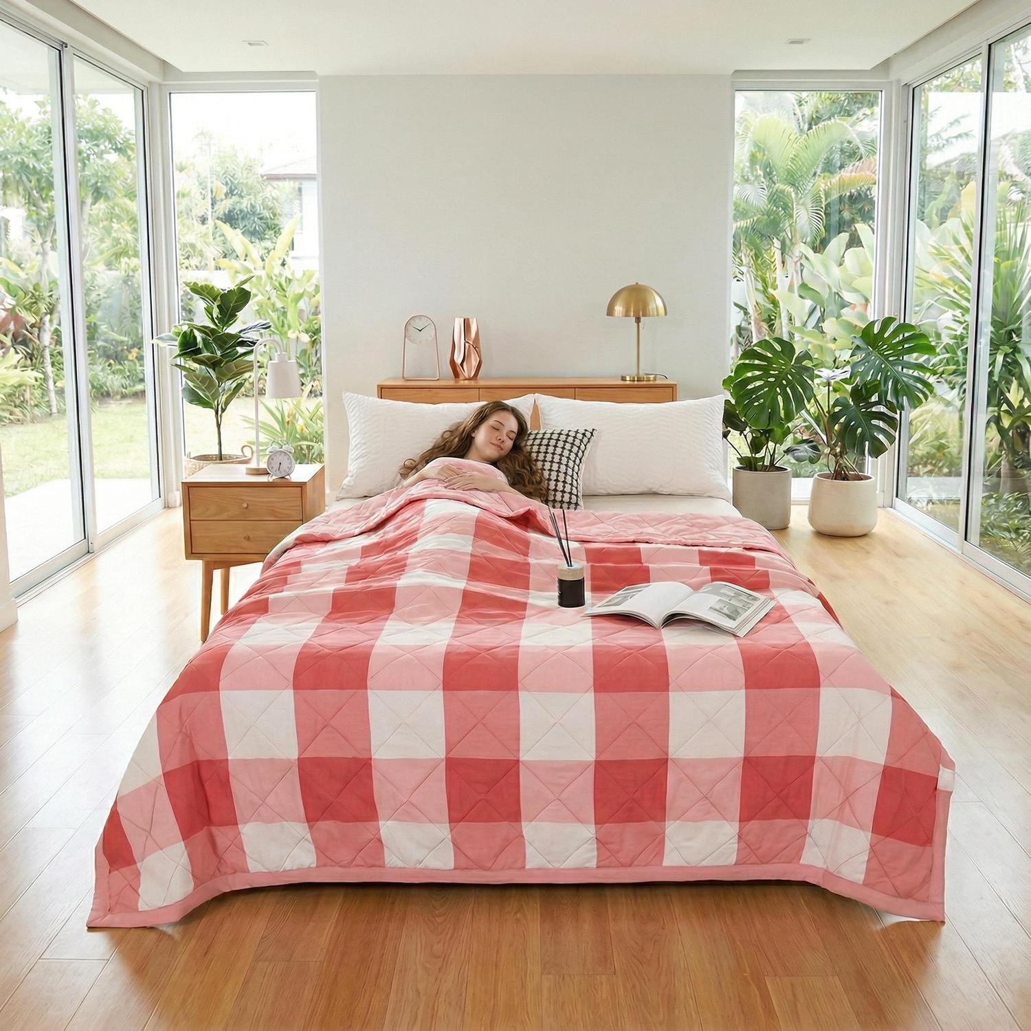 Red and white plaid lightweight polyester summer quilt on a bed with a woman sleeping.