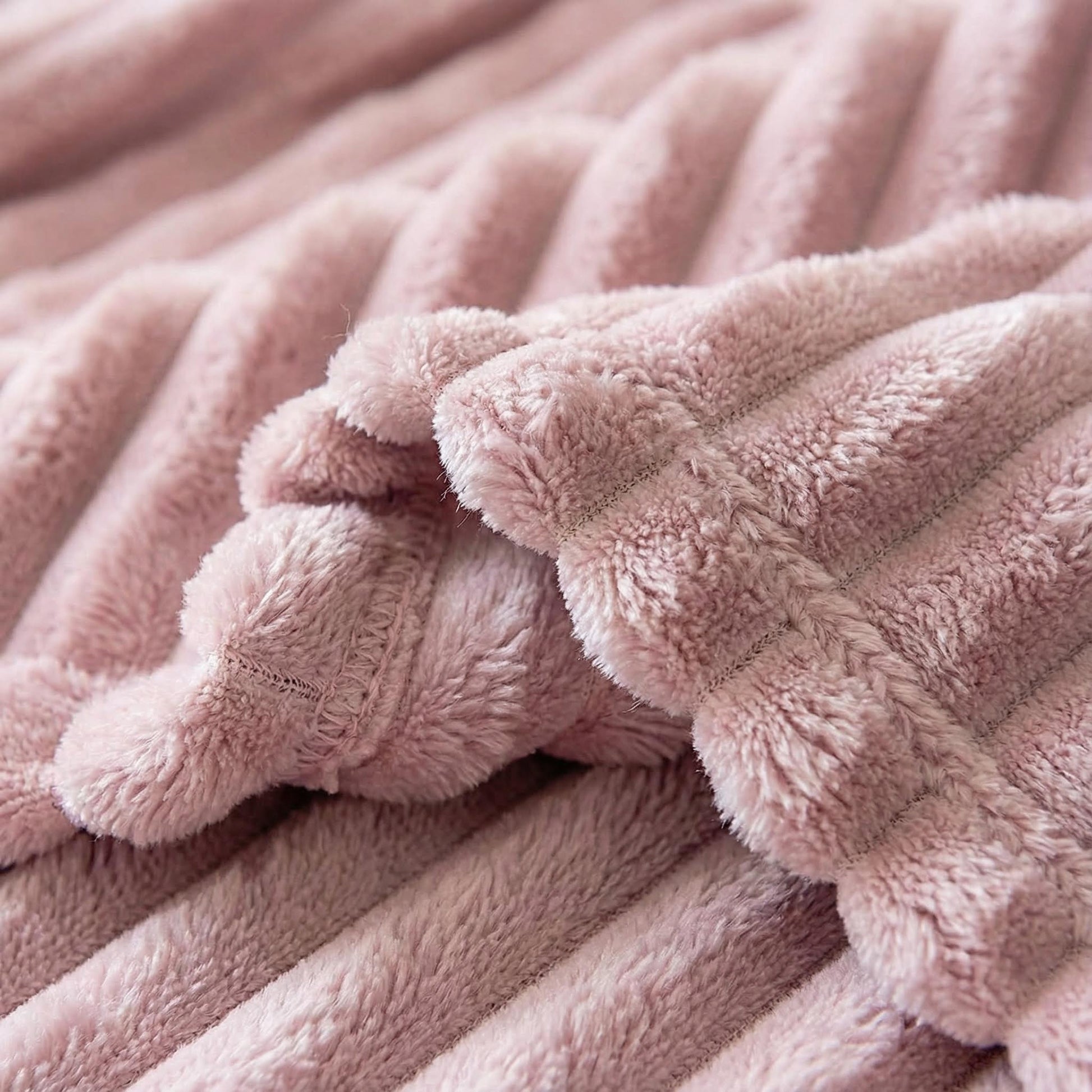 Soft pink plush faux fur throw blanket with a striped, ribbed texture.