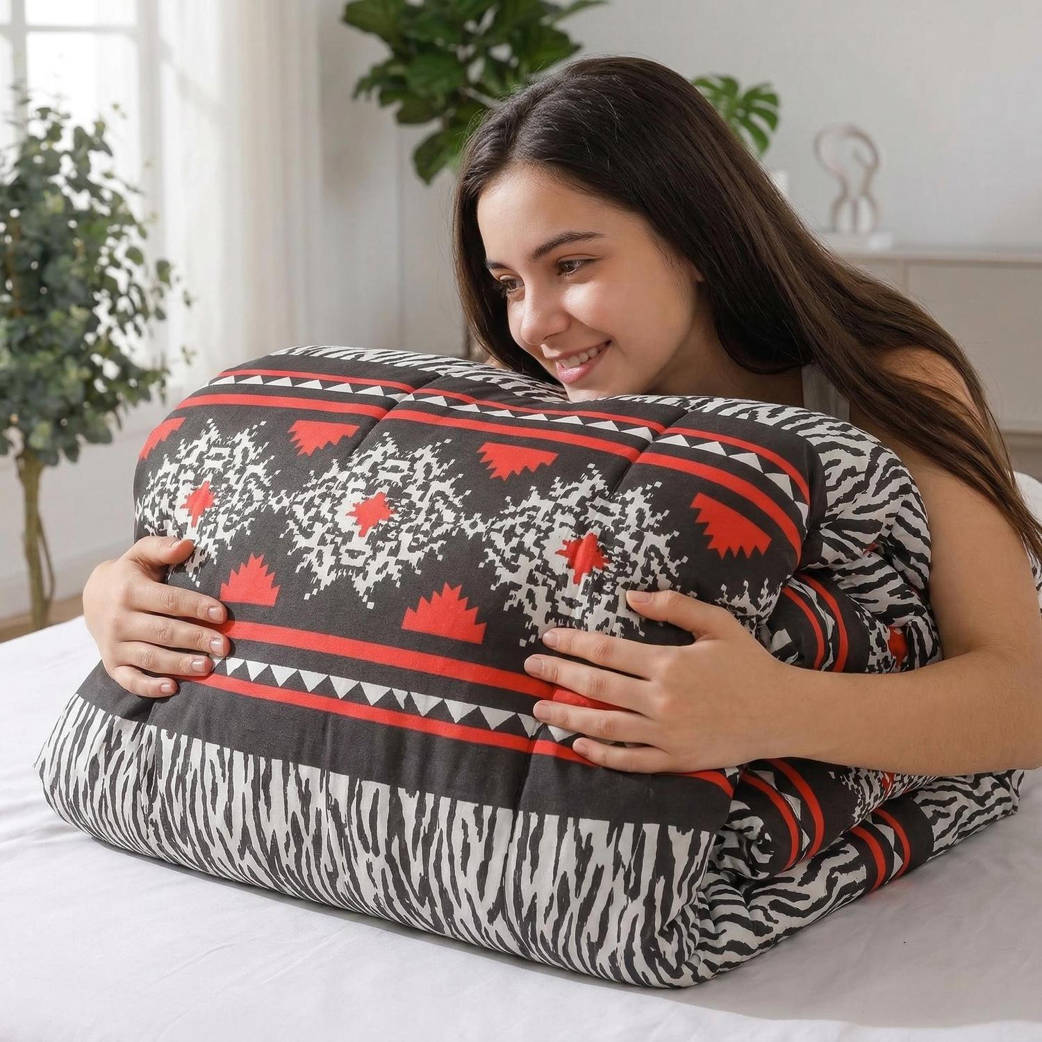 Smiling woman hugging a soft, quilted comforter with black, red, and white geometric patterns.
