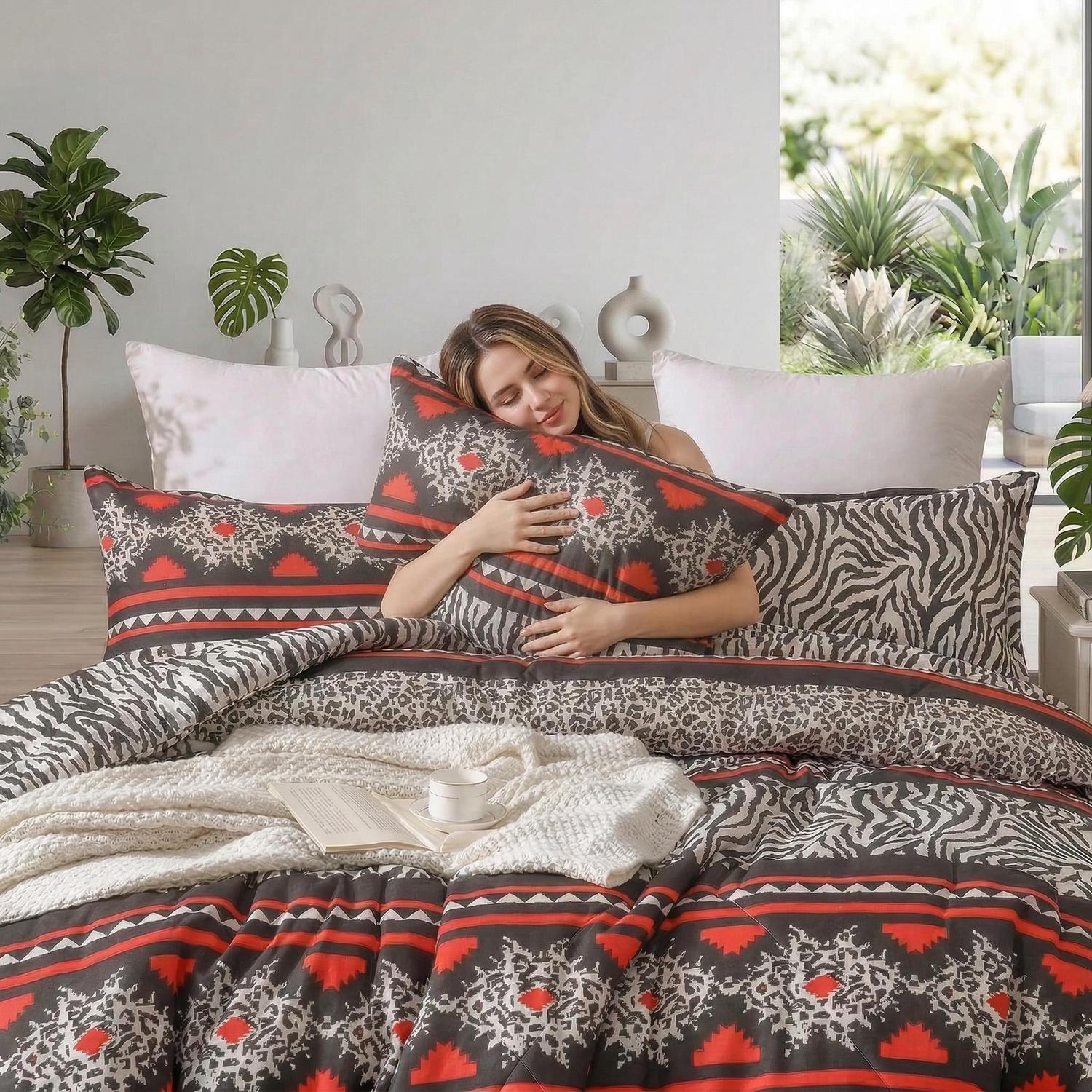 Woman relaxing on a bed with a 3-piece quilted comforter set featuring a tribal and zebra print.